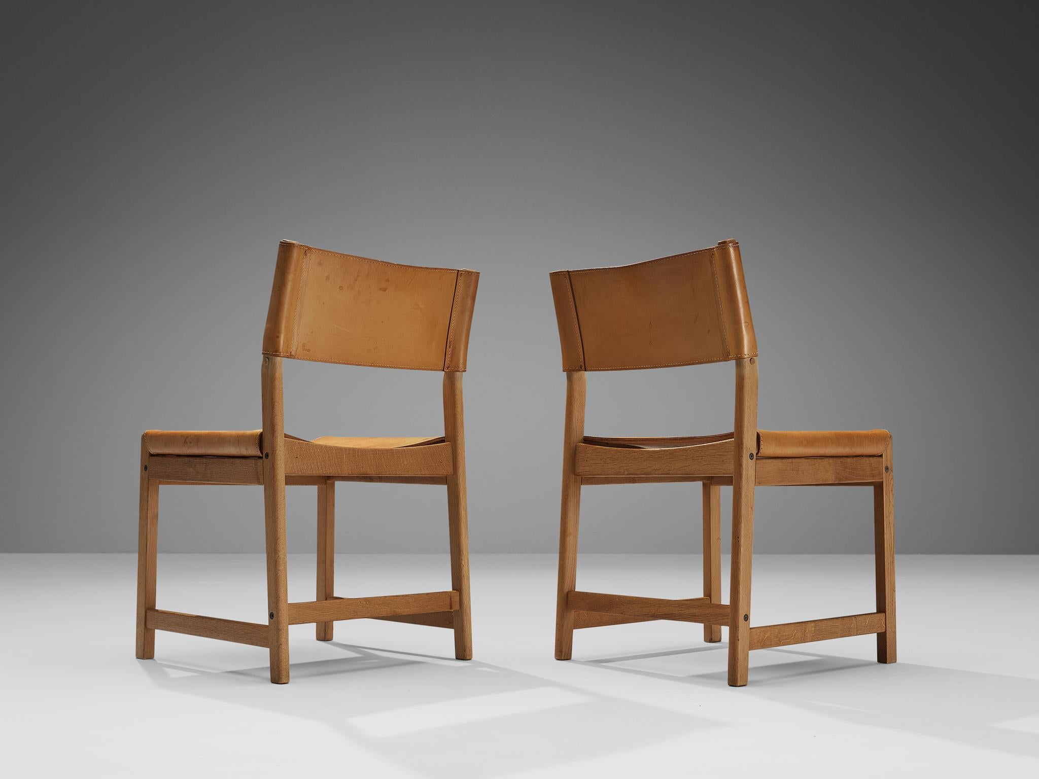 Kurt Østervig for Sibast, pair of dining chairs, cognac leather, oak, Denmark, 1960s. 

These characteristic chairs are made in solid oak, with seating and back from thick cognac leather. The lines and forms are simple, yet with the right amount of