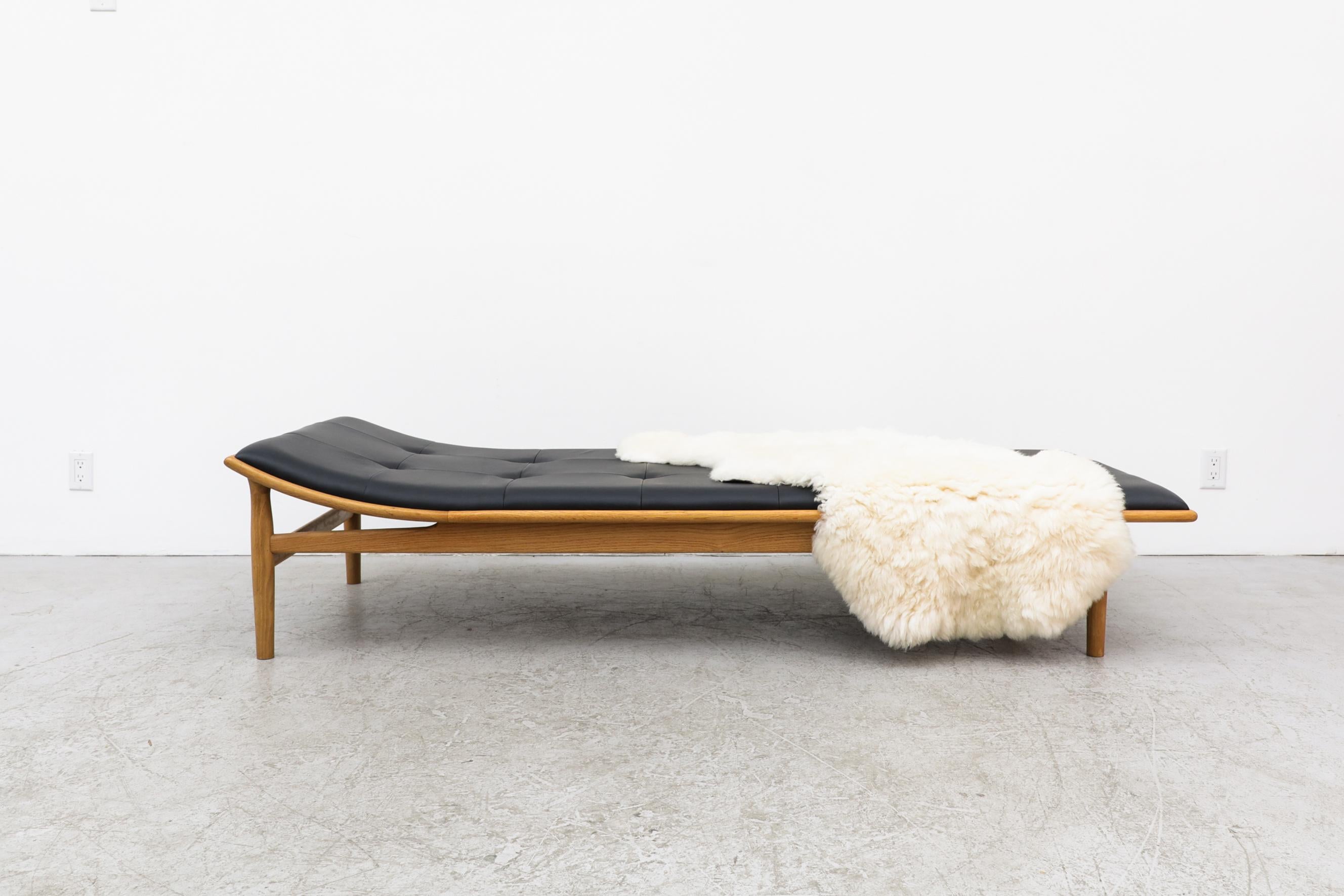 Kurt Østervig re-issue Model 311 oak daybed designed in the 1950s. A sleek wooden frame with a thin tufted black leather upholstered cushion. In good original condition with minimal wear, consistent with its age and use. Retains makers label. Three