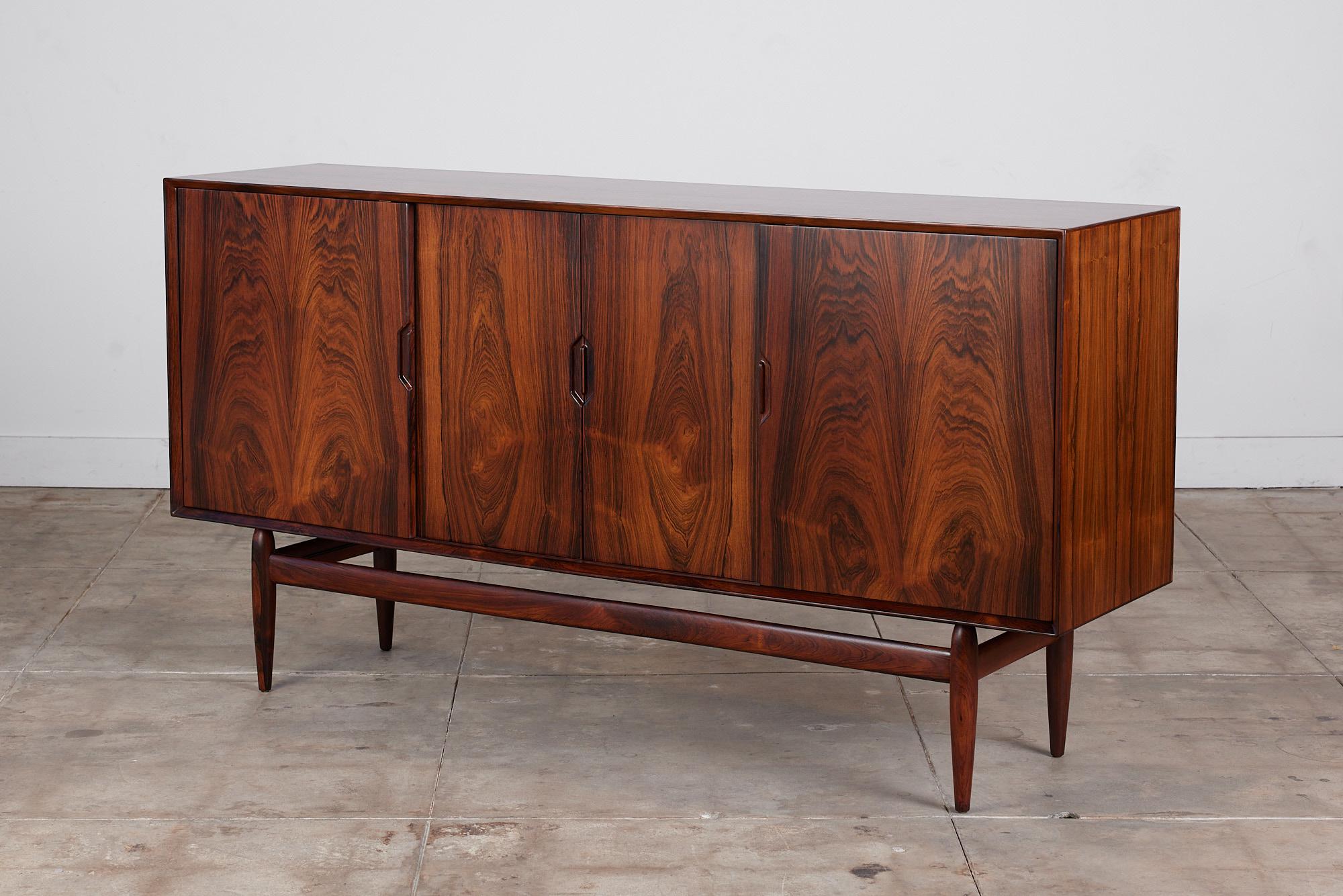 A striking rosewood credenza by Danish born designer Kurt Østervig for Brande Mobelindustri, circa 1960s, Denmark. The credenza features four sliding rosewood doors with beautiful wood grain. The two center doors open to reveal seven storage drawers