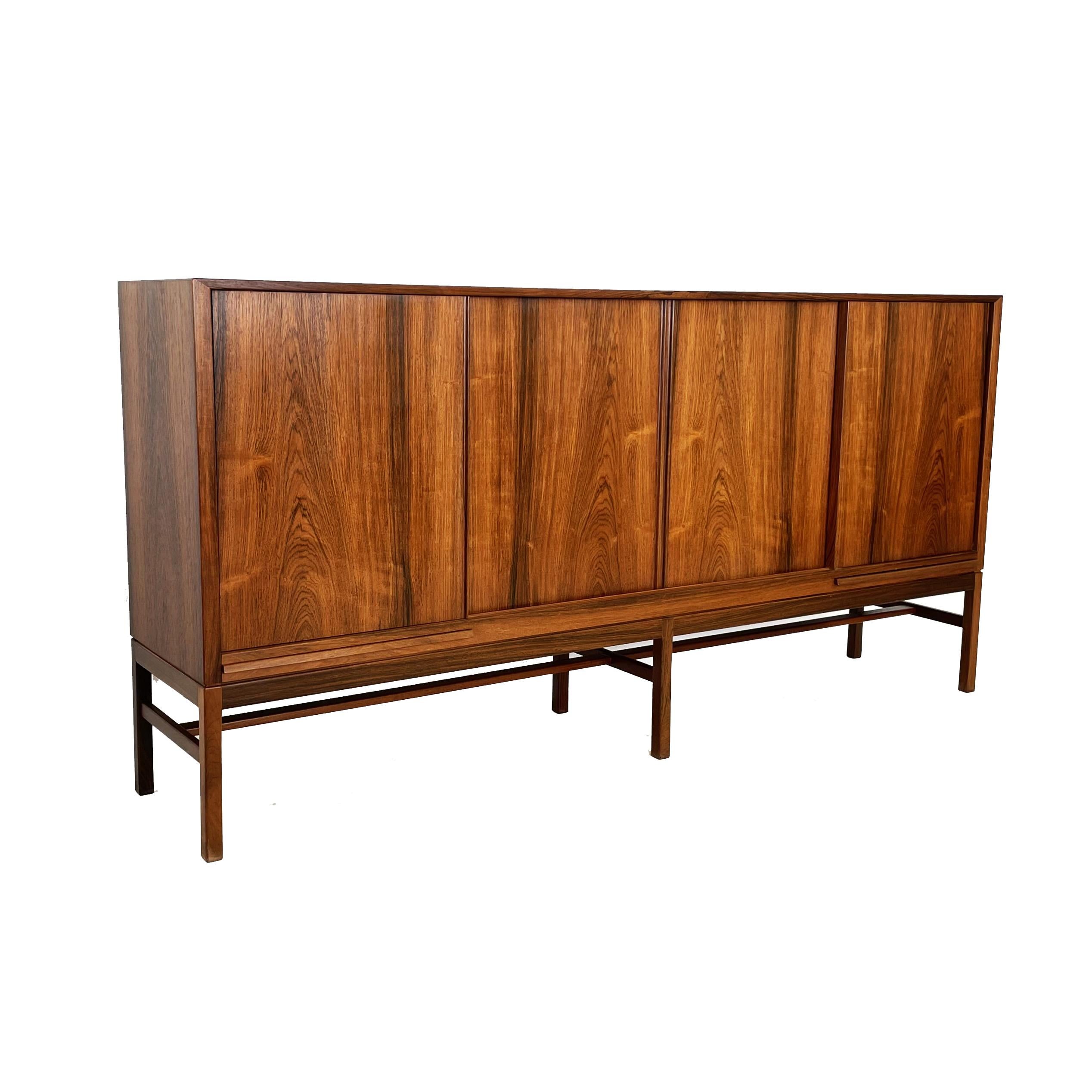 Very nice and rare Kurt Østervig sideboard. Mid-Century Brazilian Rosewood with  book-matched grain on four sliding doors. Interior in light oak. Shelves on the inside, five beautifully handcrafted drawers with detailed inserts.  Adjustable shelves.