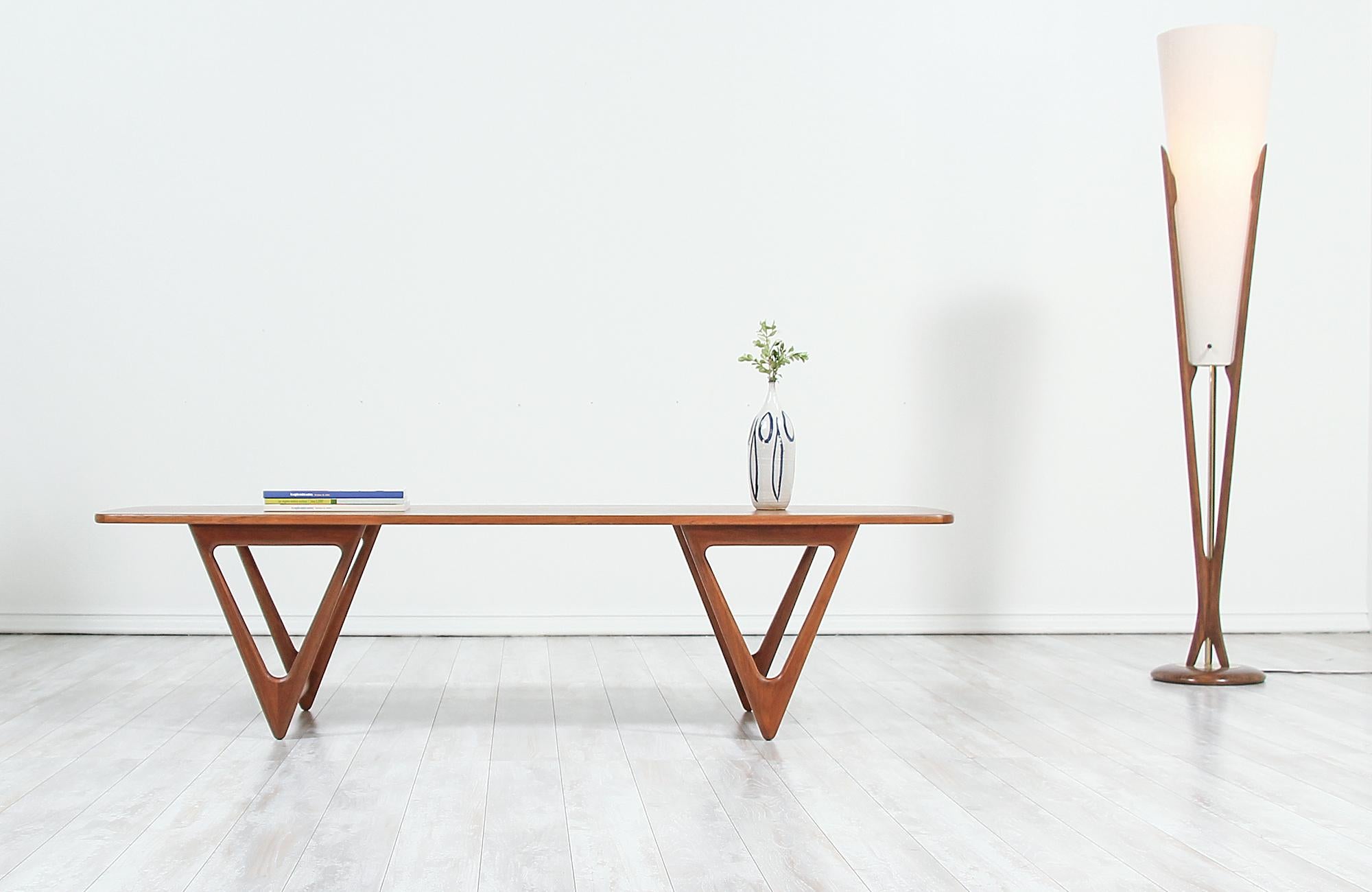 Sculpted modern surfboard coffee table designed by Kurt Østervig or Jason Møbler in Denmark, circa 1950s. This stunning carved coffee table features a sturdy teak wood construction with unique triangular legs showcasing the geometric aesthetic of