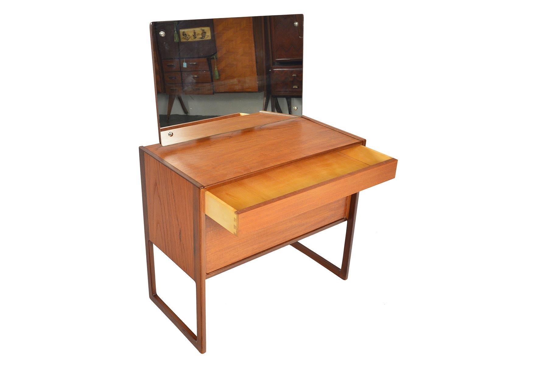 This adorable teak vanity was designed by Kurt Østervig in the 1960s. The case stands on integrated sleigh legs and offers a single drawer and a lower drop down cabinet. Above the case is an articulating mirror. In excellent original condition.

 