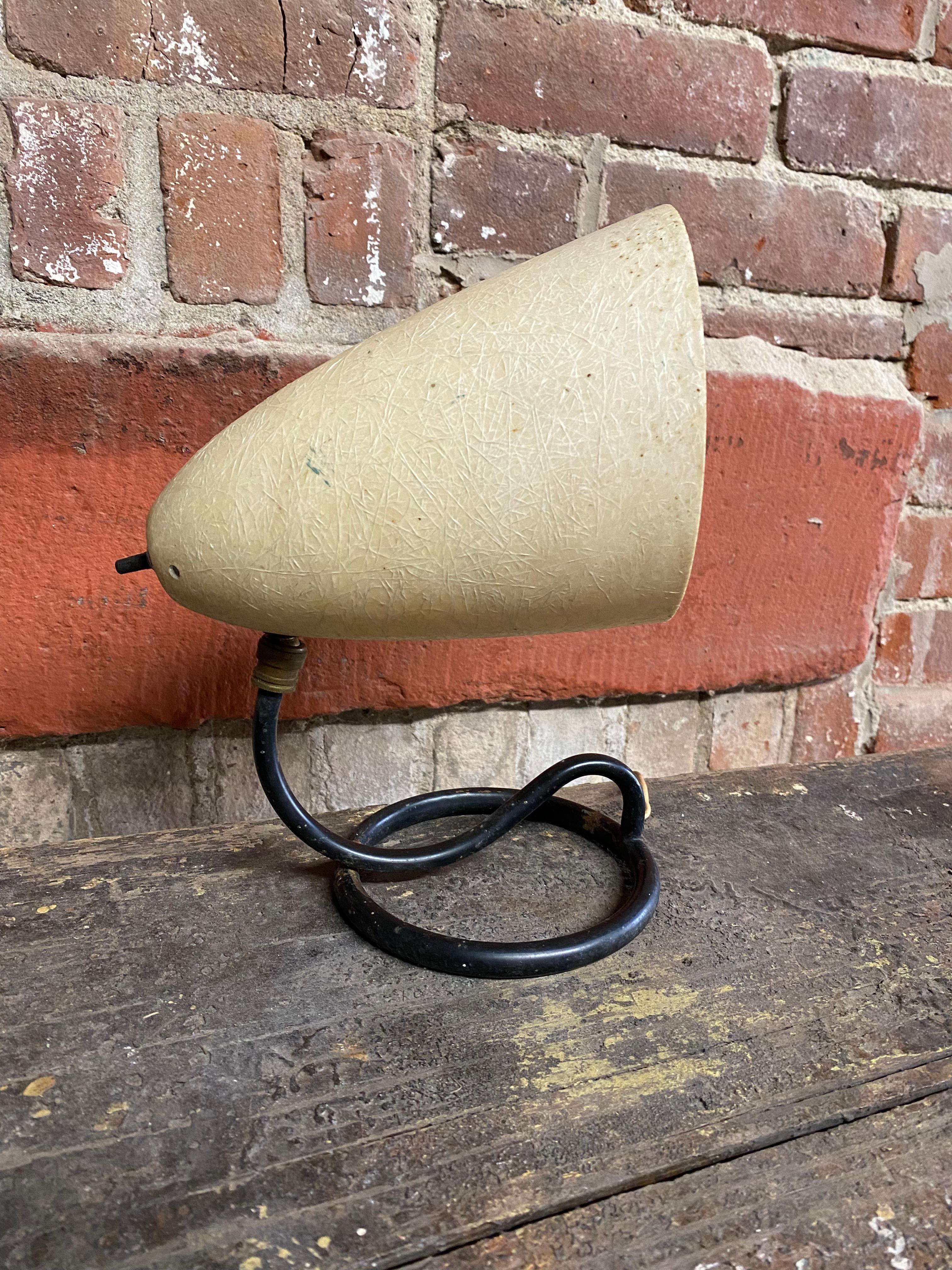 Parchment fiberglass cone with a black enamel coiled serpentine metal base lamp that can either be used as hanging wall sconce or shelf or table top spotlight type lamp. Circa 1950. Good overall condition with some minor surface wear to the metal
