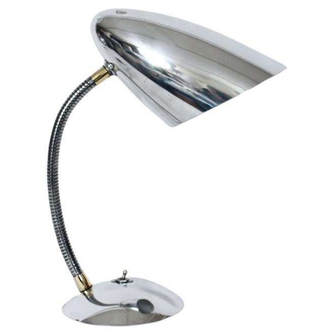 Lampada da scrivania regolabile in alluminio lucido in stile Kurt Versen, anni '50. Caratterizzata da una colonna a collo d'oca regolabile e ricurva, da un paralume a cono in alluminio lucidato e da una base in alluminio a cupola e in ferro