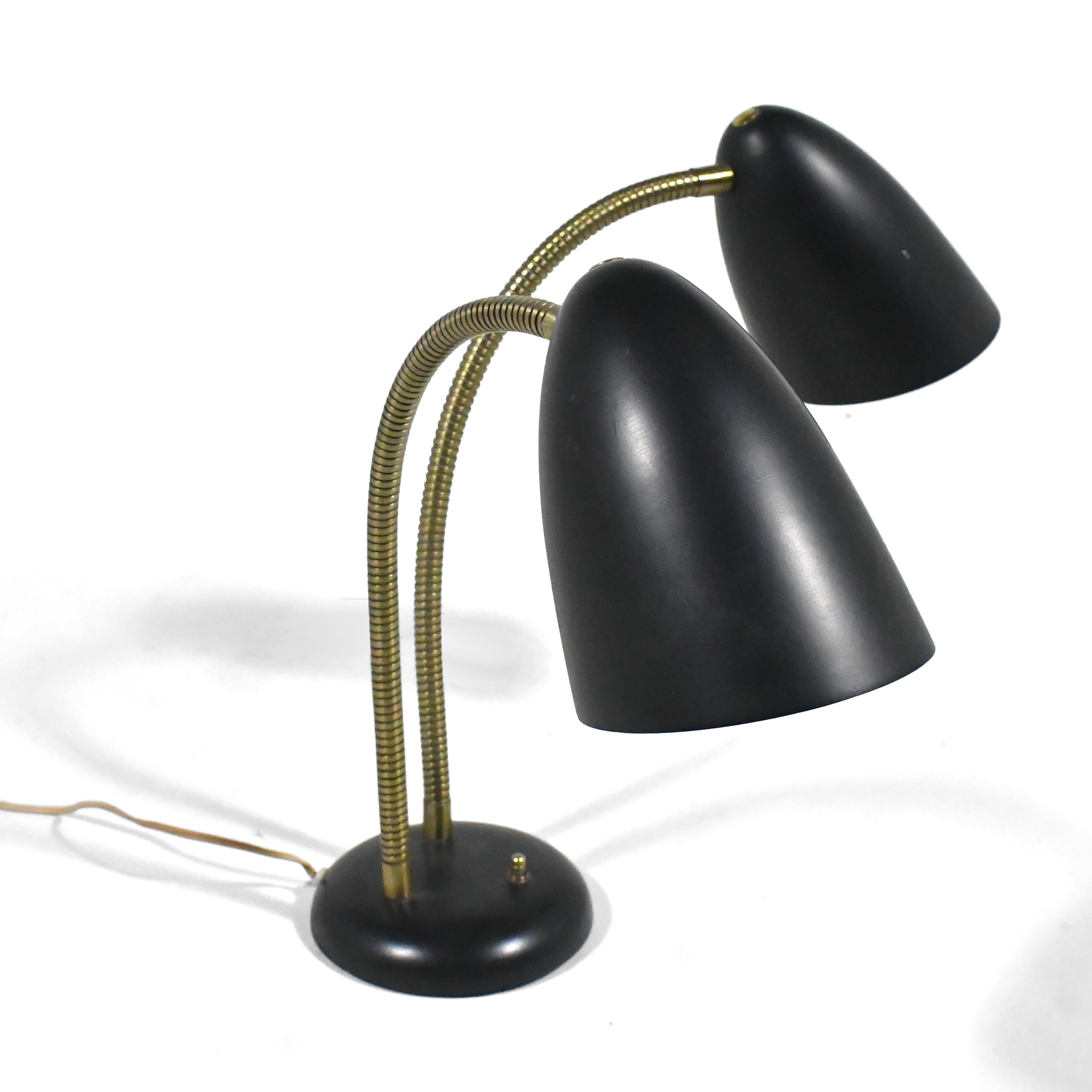 Design fonctionnaliste classique d'après-guerre de Versen, cette lampe de table comporte deux abat-jours coniques en aluminium filé reliés à la base par des cols de cygne flexibles.

Les dimensions varient, mais mesurent 17,5 