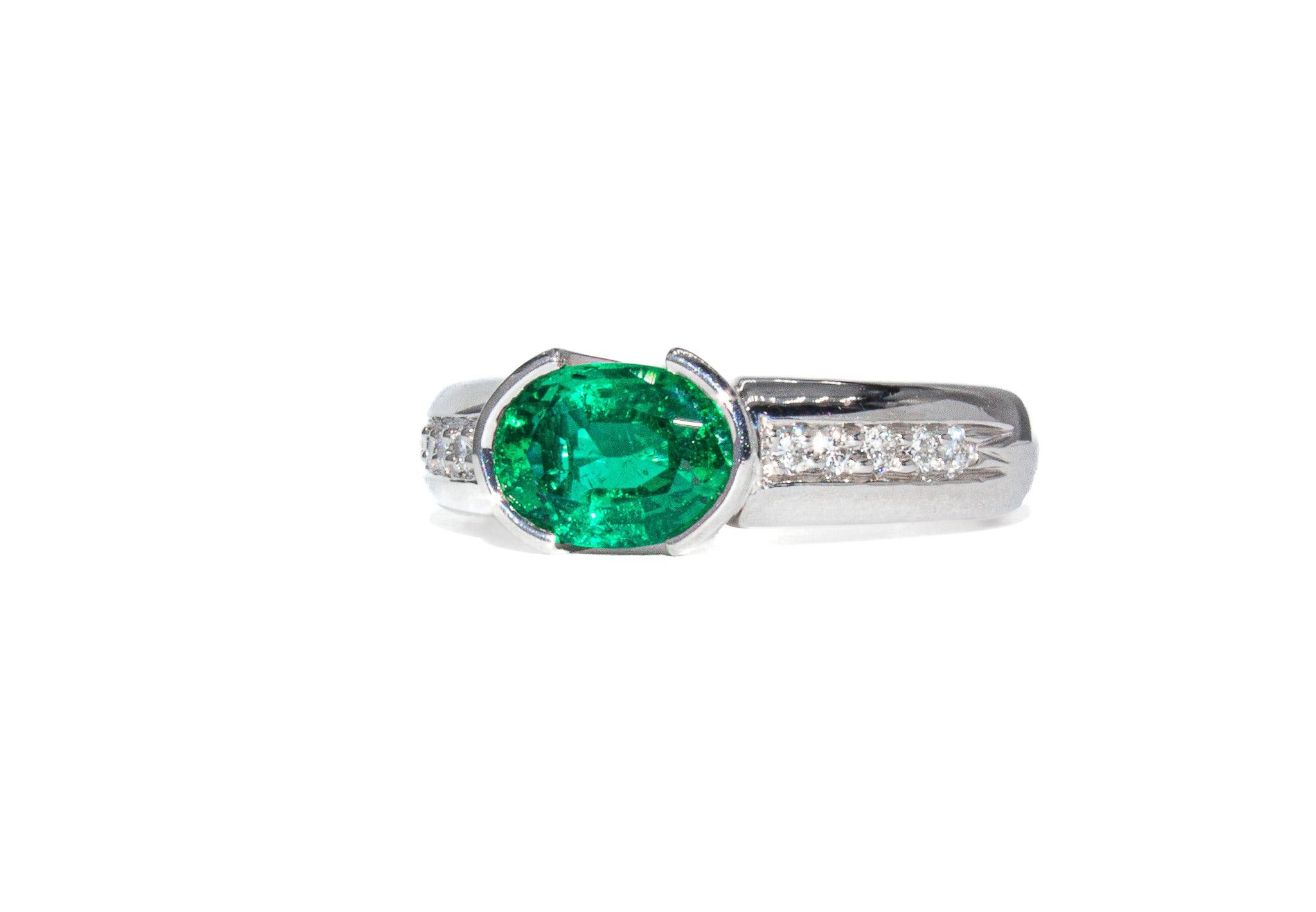 Dieser signierte Smaragd- und Diamantring von Kurt Wayne ist ein lebhaftes und elegantes Stück von einem berühmten amerikanischen Designer. Sein Herzstück ist ein farbenprächtiger ovaler Smaragd von 1,20 Karat, der in einer Lünette gefasst ist, um