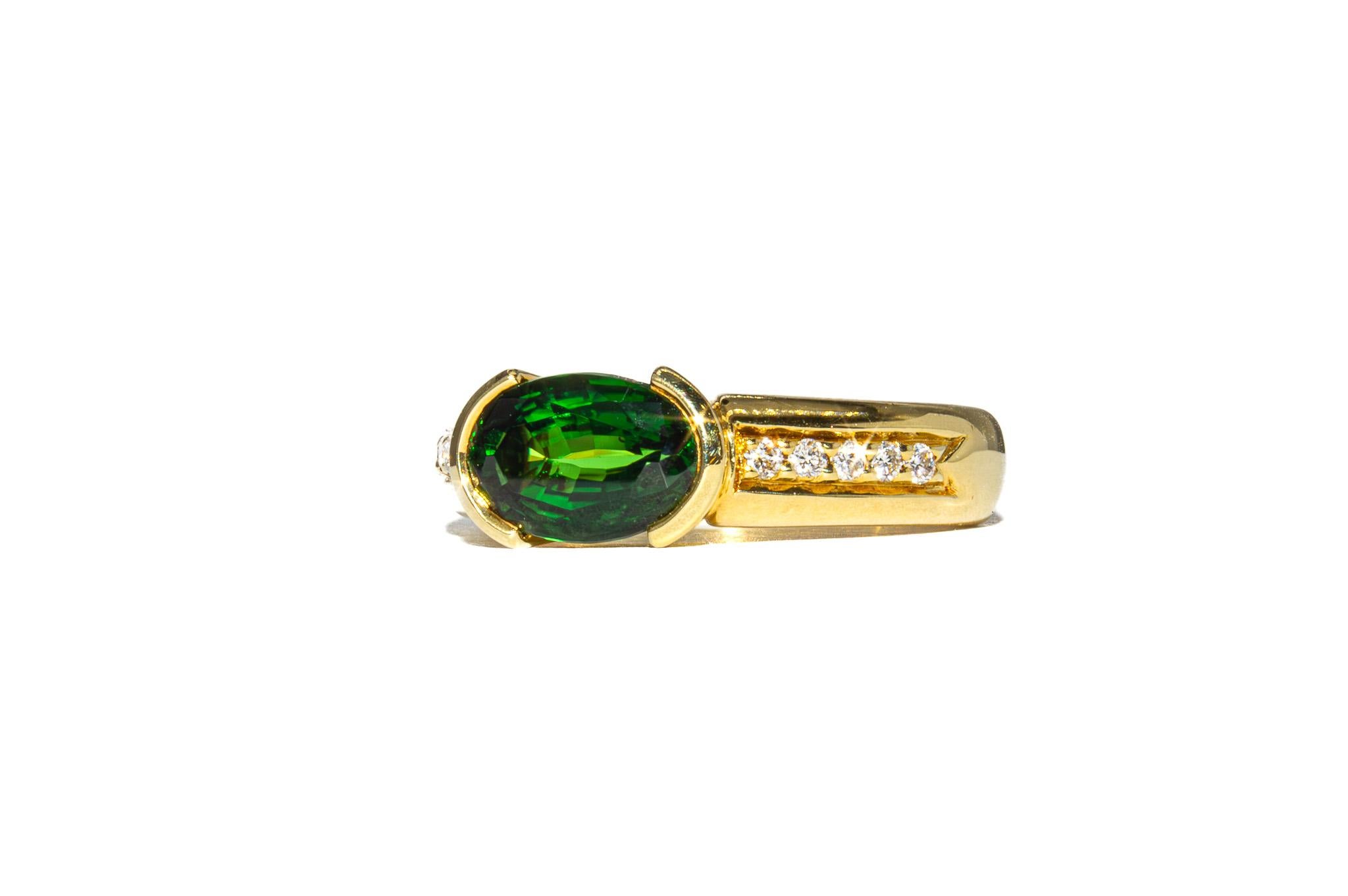 This charming vintage ring is a warm and vibrant piece that brings together classic craftsmanship and rich color. At its center is a 1.78 carat oval green tourmaline with a lush, saturated hue. The stone is bezel-set to highlight its clean lines and