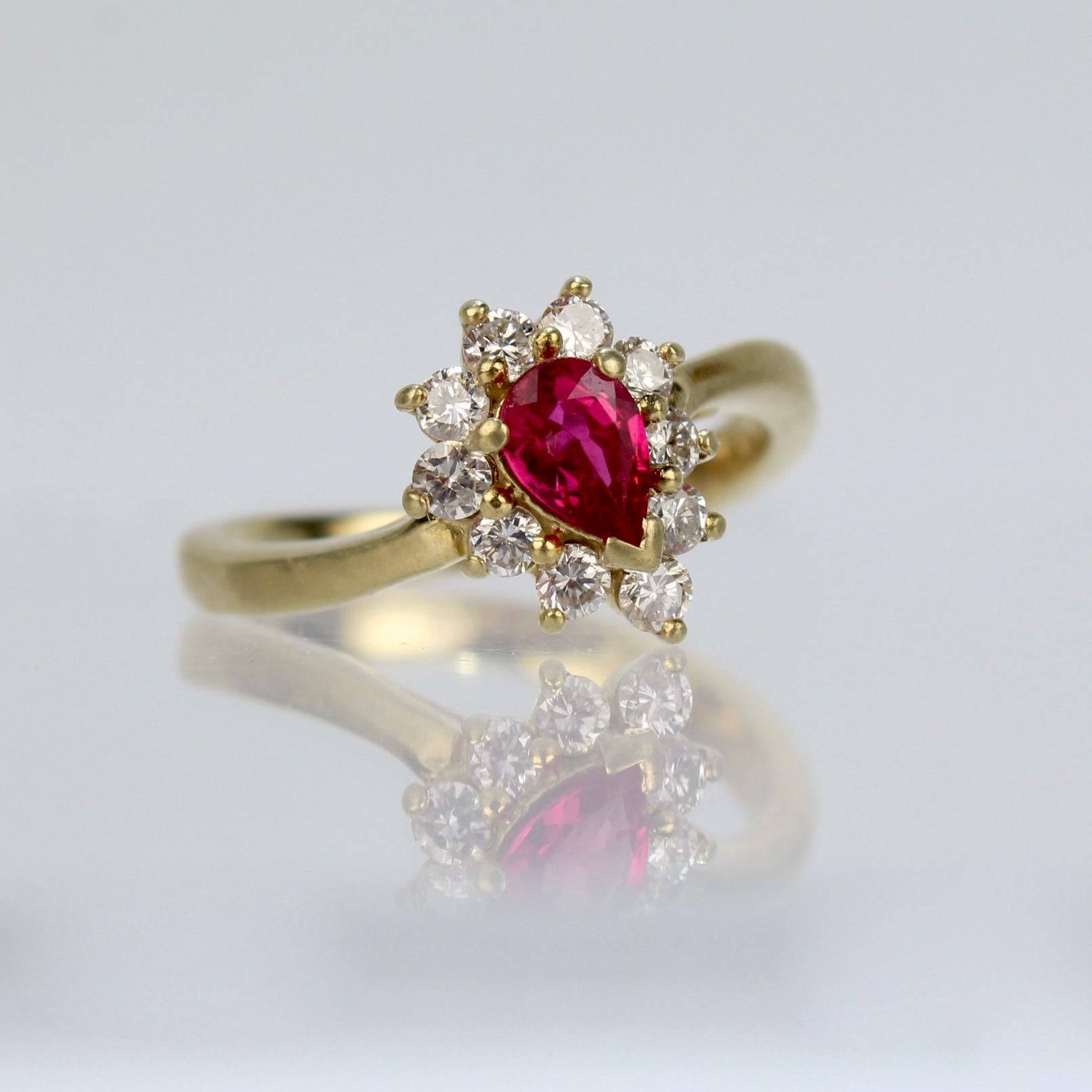 A wonderful cocktail ring by Kurt Wayne.

In 18K yellow gold with a half-twist to the shank. The shank supports a gallery with a central pear-cut ruby and 10 small round cut diamonds. 

A high-level ring from the famous New York jewelry