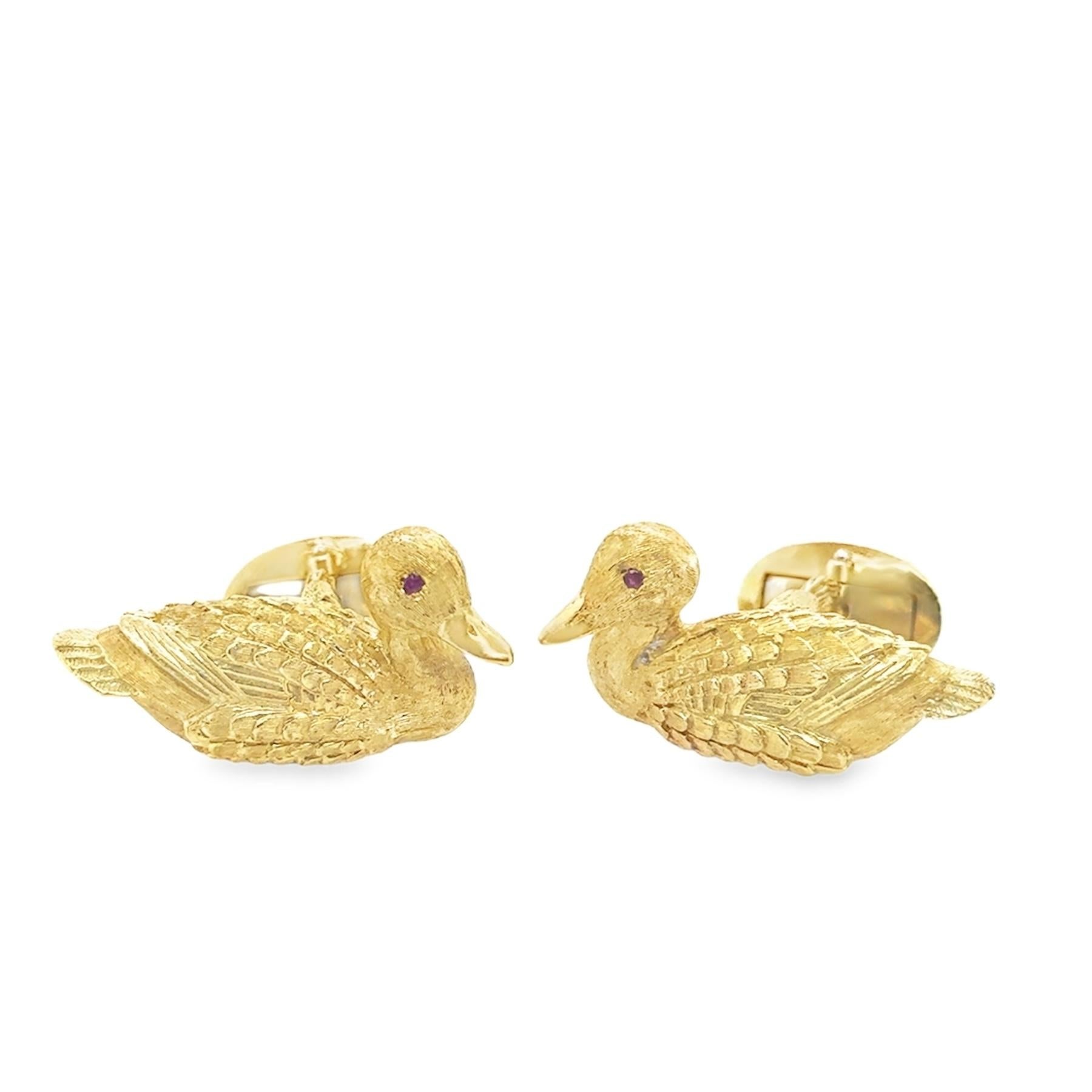 Eleganza del design di Kurt Wayne. Questa coppia di gemelli è realizzata in oro 18 carati. La coppia presenta squisite pietre di rubino incastonate come occhi di figure di anatre intricate e dettagliate. L'oro presenta un motivo strutturato che