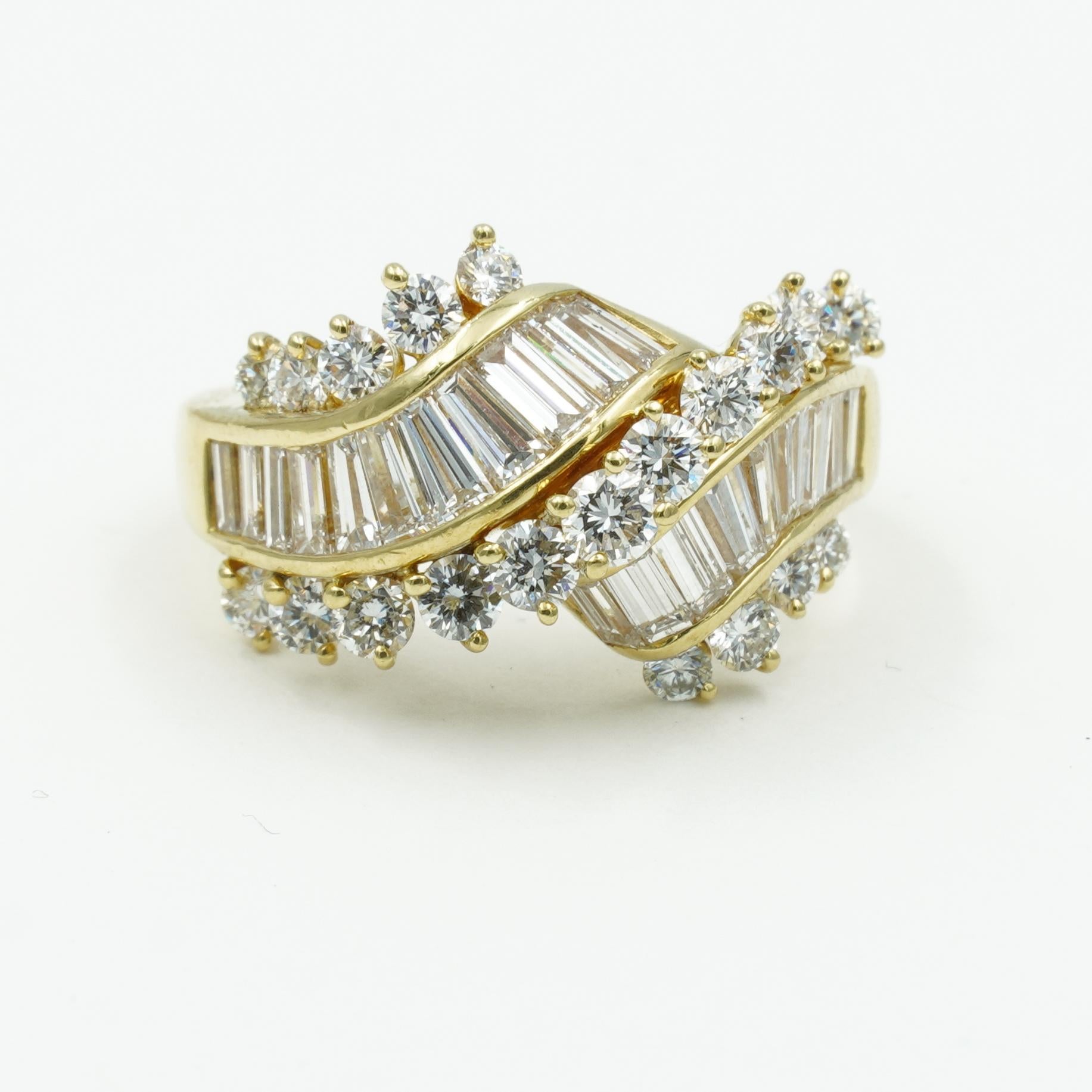 Designed by Kurt Wayne, this vintage cocktail ring is the perfect statement piece for your jewelry wardrobe. It contains a total of 18 baguette diamonds and 19 round brilliant cut diamonds totaling 2.40 carats throughout the ring. The diamonds are