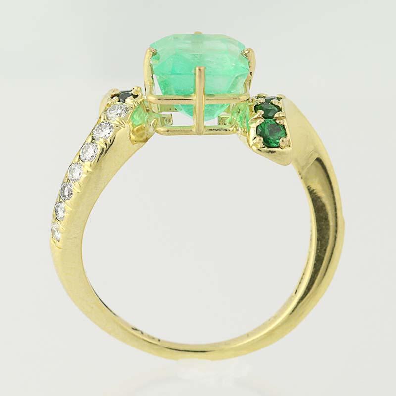 The essence of dreams! Exquisitely crafted by Kurt Wayne, this 18k yellow gold ring is fashioned in a junoesque bypass design which showcases a radiant emerald solitaire accompanied by Tsavorite garnets and shimmering diamonds. The ring’s shank is