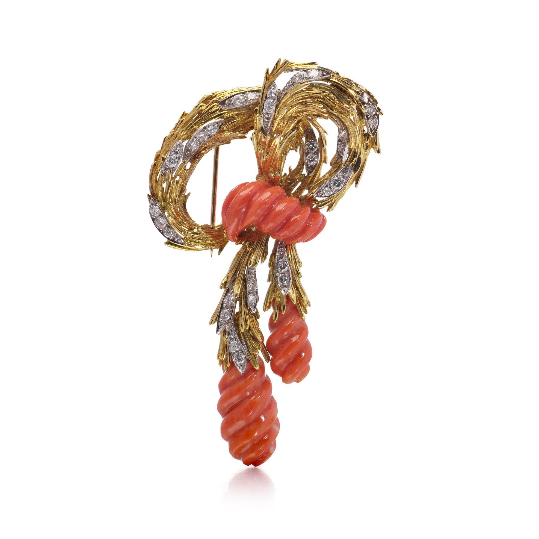 Llamativo broche vintage de Kutchinsky, fabricado hacia 1970 en oro blanco y amarillo de 18 quilates. Este atrevido diseño presenta un cabujón central de coral natural, de aproximadamente 3 cm x 1,3 cm, que irradia un color cálido y orgánico. Rodean