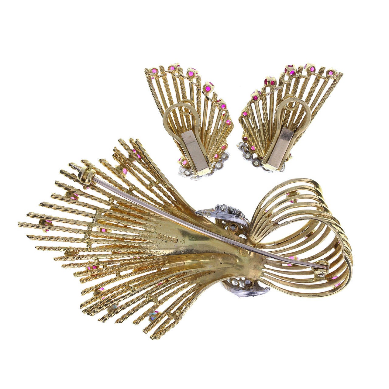18 carat yellow gold wires twisted to form a spray brooch and matching pair of earrings. Set with round brilliant-cut diamonds on a central white gold wrap on the brooch, with randomly placed, round-cut rubies. Earrings set with a border of diamonds