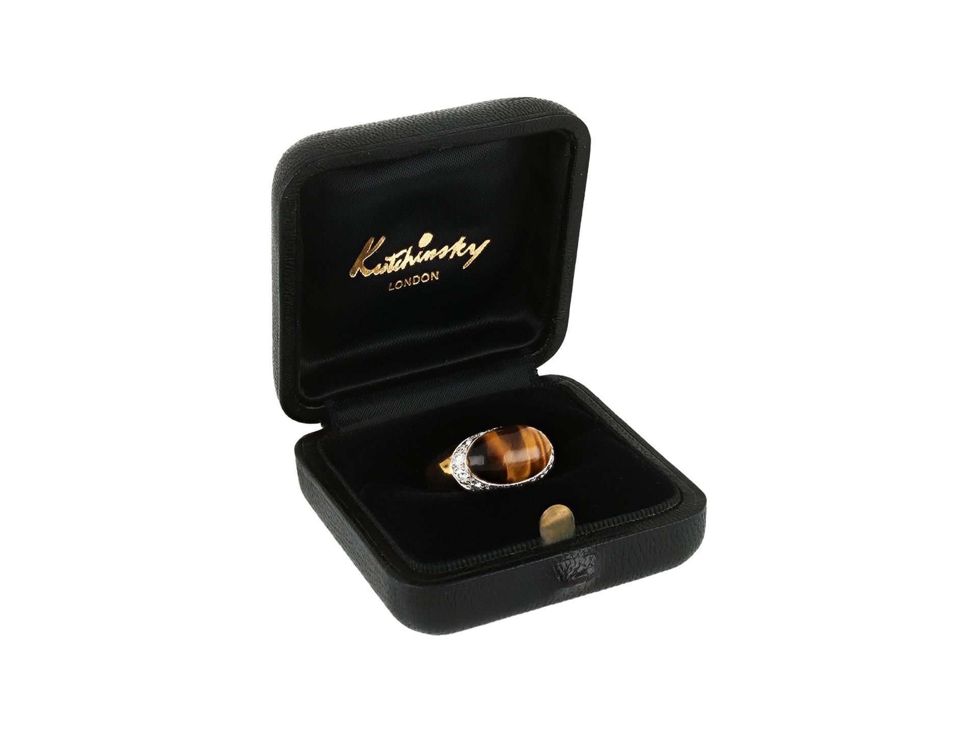 Bague en œil de tigre et diamants de Kutchinsky. Au centre, un œil de tigre naturel cabochon de forme ovale en serti-retour ouvert d'un poids approximatif de 2,00 carats, entouré de seize diamants ronds de taille brillant en serti-retour ouvert d'un