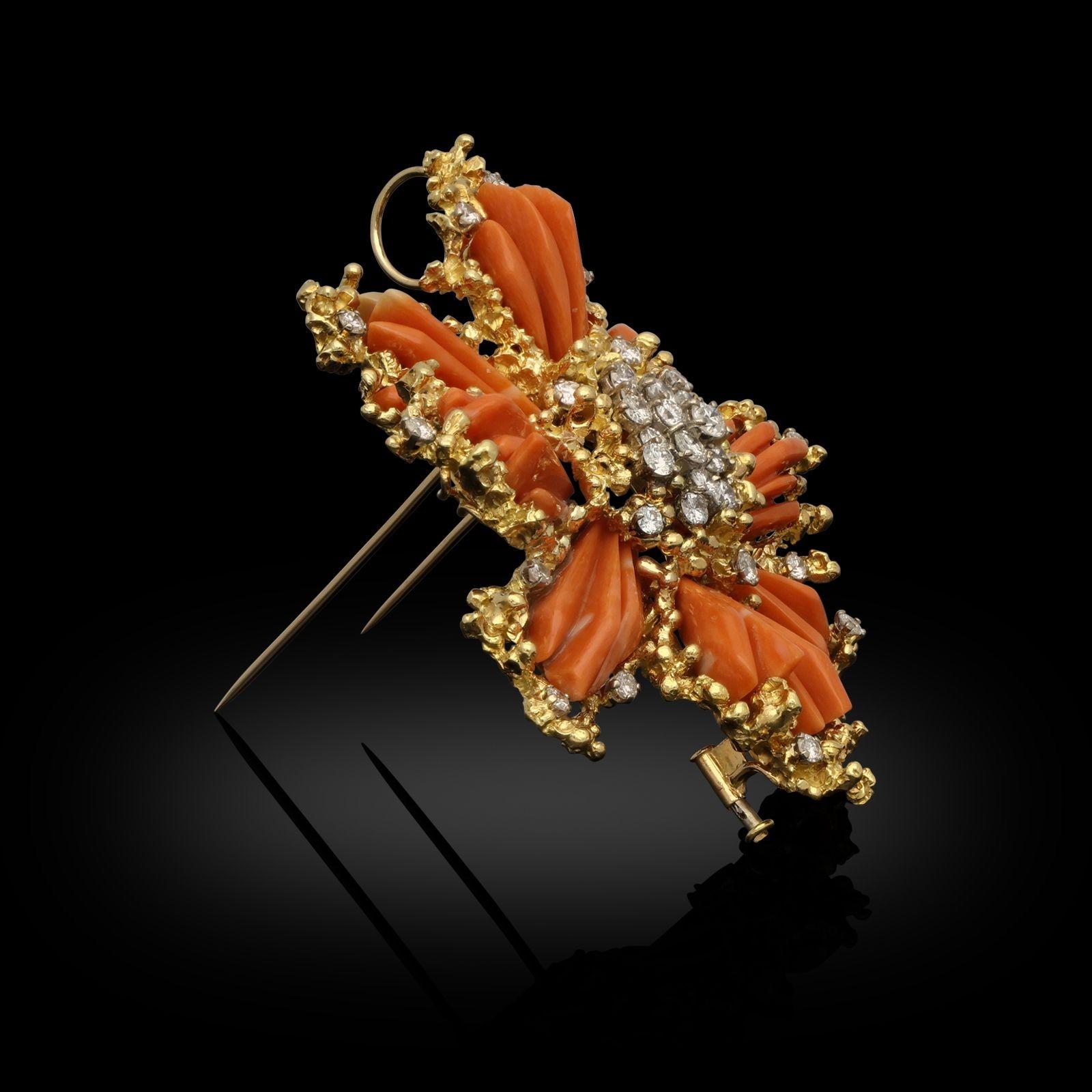 An 18ct yellow gold, coral and diamond brooch by Kutchinsky 1969. The clip brooch is a star-burst design and formed of a central cluster of round brilliant cut diamonds in claw settings within an organic textured gold surround. Eight pieces of
