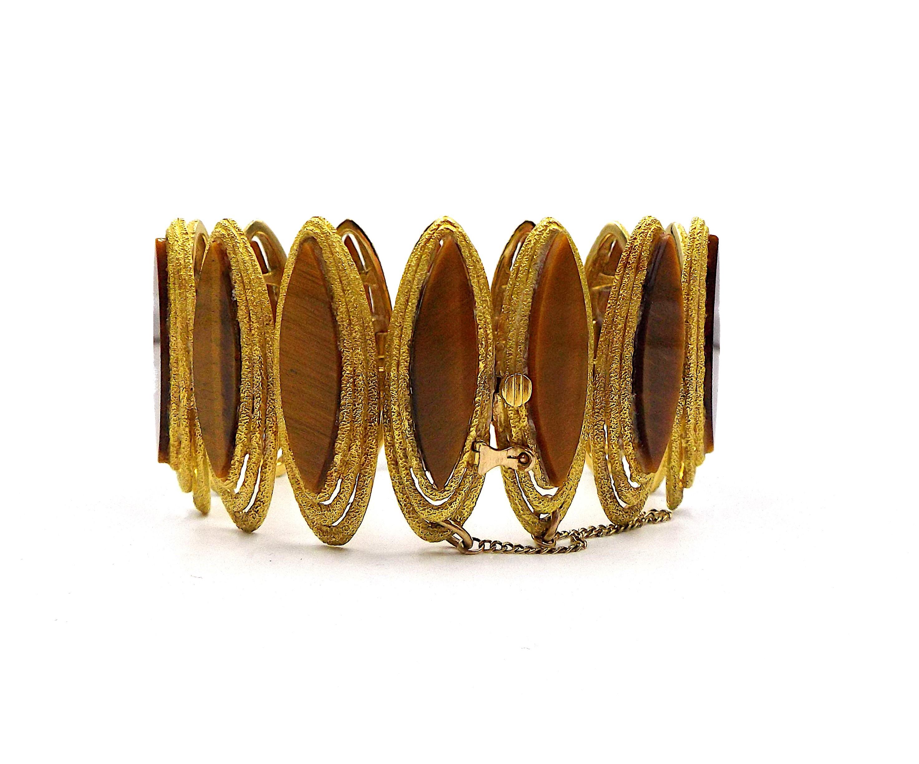 Of textured design, featuring elongated links inlayed with marquise-shaped tiger's eye quartz; set in 18k gold; internal circumference: 6 3/4 in.; signed Kutchinsky, numbered, with English hallmarks