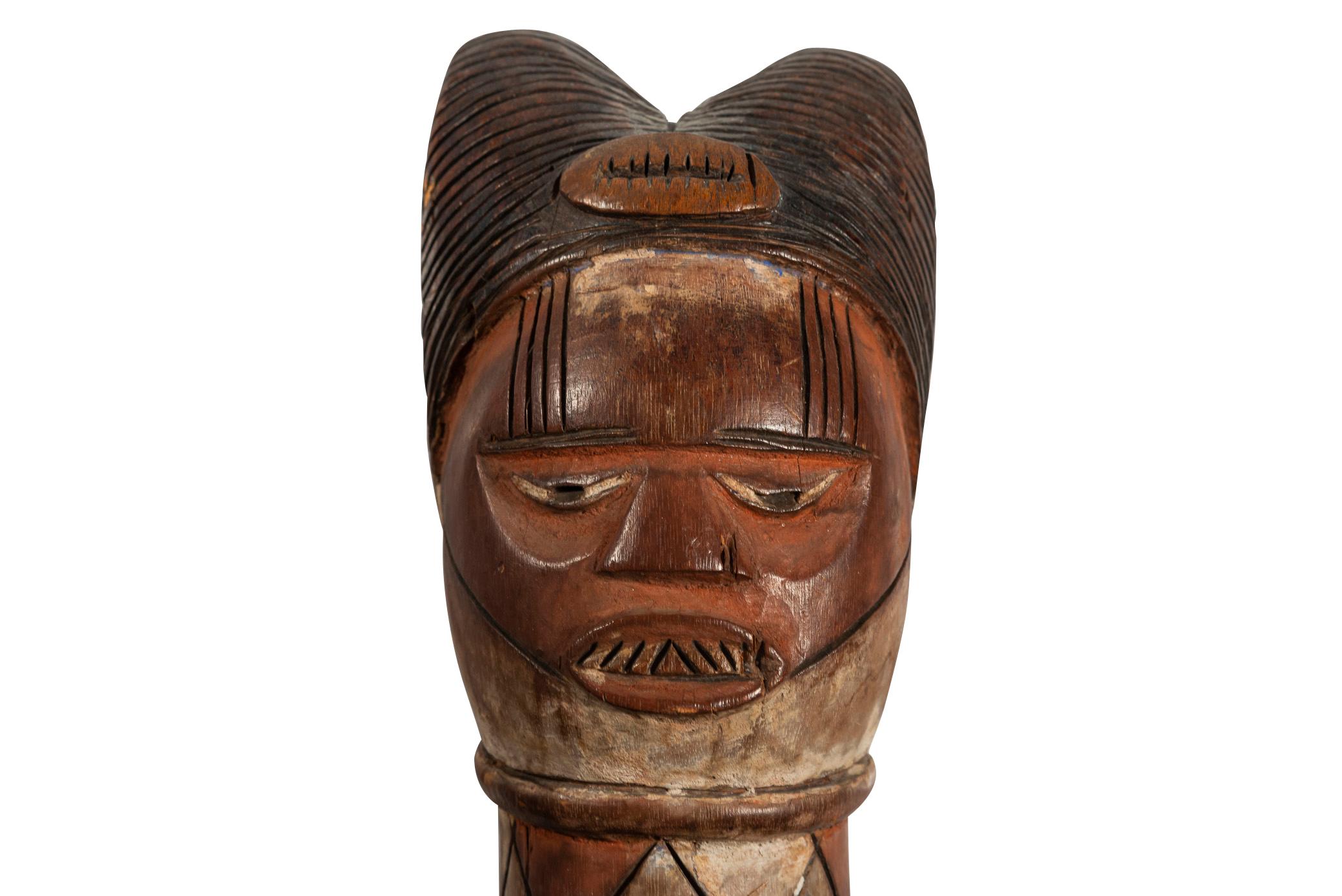 Kuyu puppet head,
Wood and white pigments,
The cylindrical handle supporting a rounded head with almond-shaped eyes, the half-open mouth revealing teeth, the neck with rows of geometric patterns, the double bun hairstyle, the face and the skull