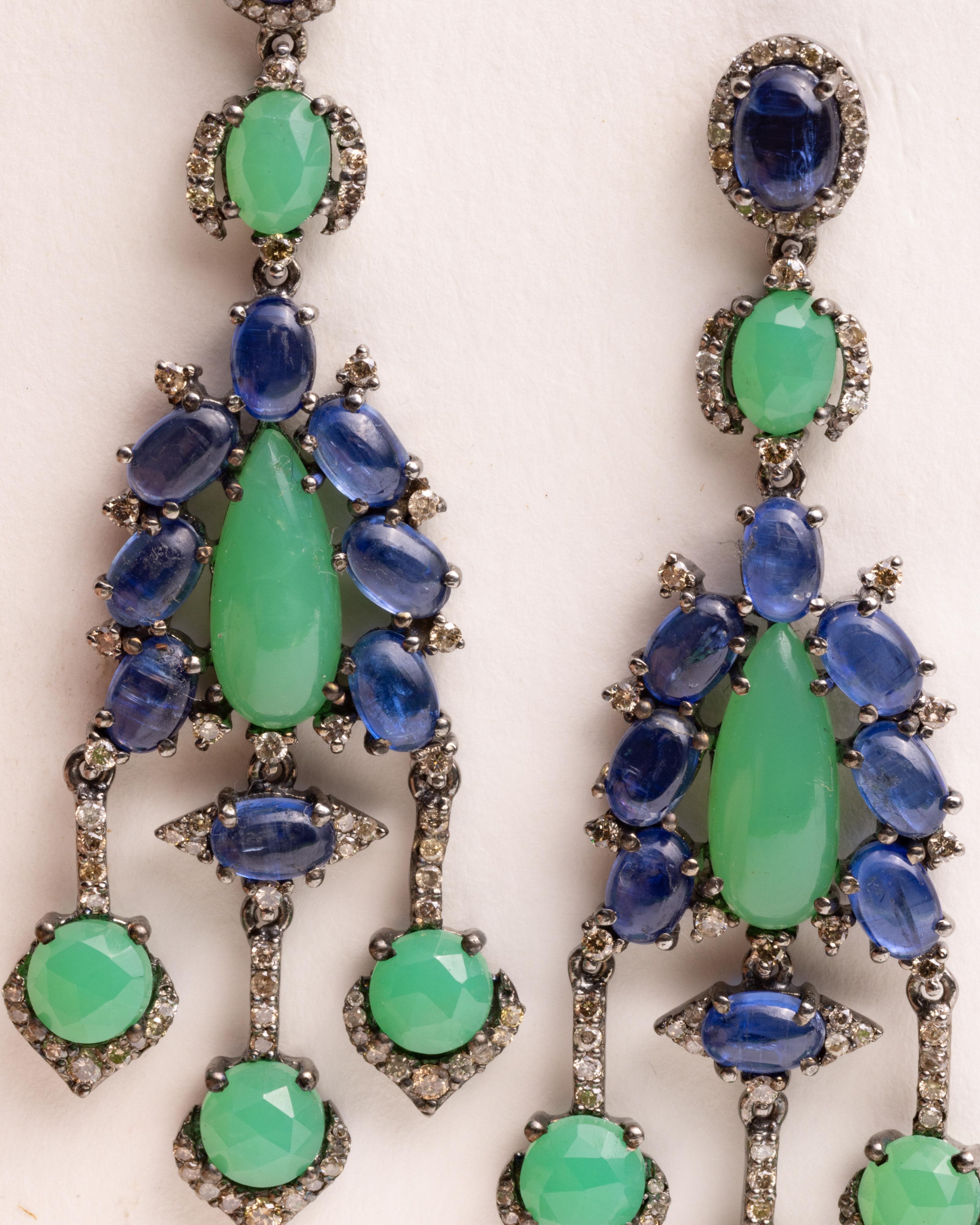 A long dramatic pair of chandelier earrings with oval, faceted kyanite gem stones, and round, faceted green chalcedony stones and a center tear drop chalcedony.  All are interspersed with round, brilliant cut diamonds.  Set in an oxidized sterling