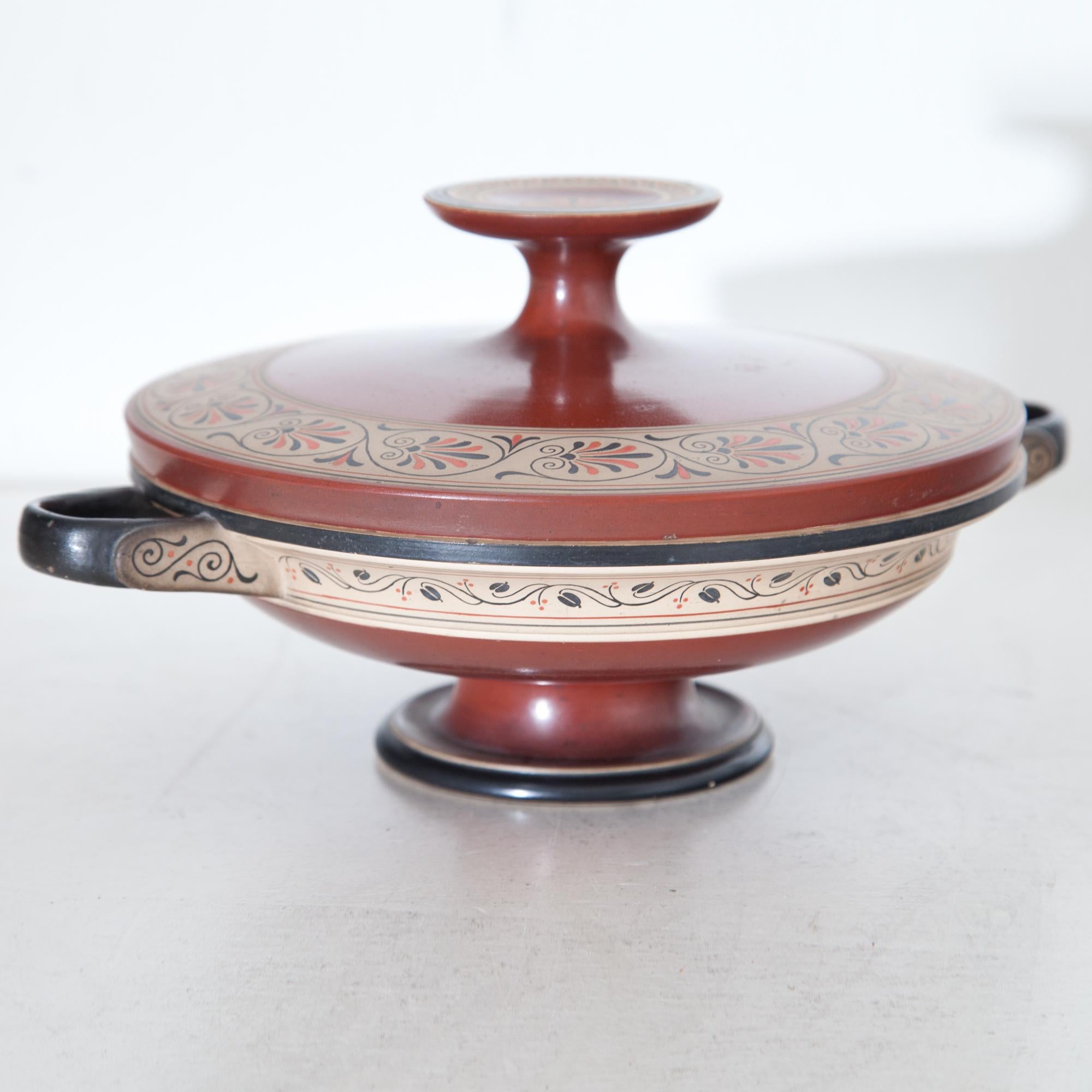 Kylix with lid by Peter Ipsen (1815-1860) from the Second Half of the 19th century. The lid and bowl are in red and decorated with acanthus leaf and tendril decorations on a beige ground, stand, handles and rim are set off in black.