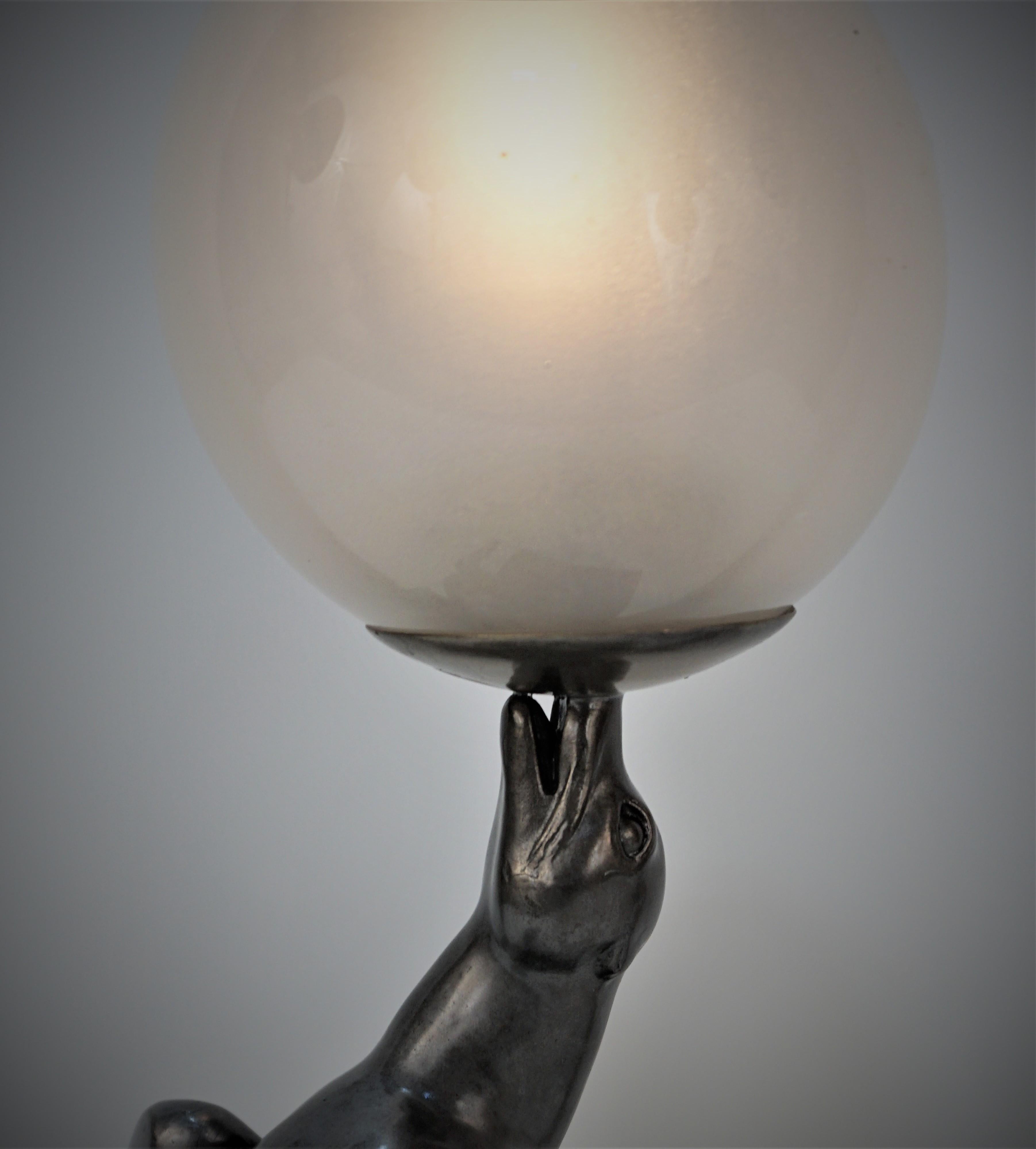 Louis-Albert Carvin - Art Deco Seelöwe Lampe, Balancierender Ball auf seinem Maul.
Glaskugel, dunkles Silber, zinnfarbenes Metall auf schwarzem Marmorsockel.