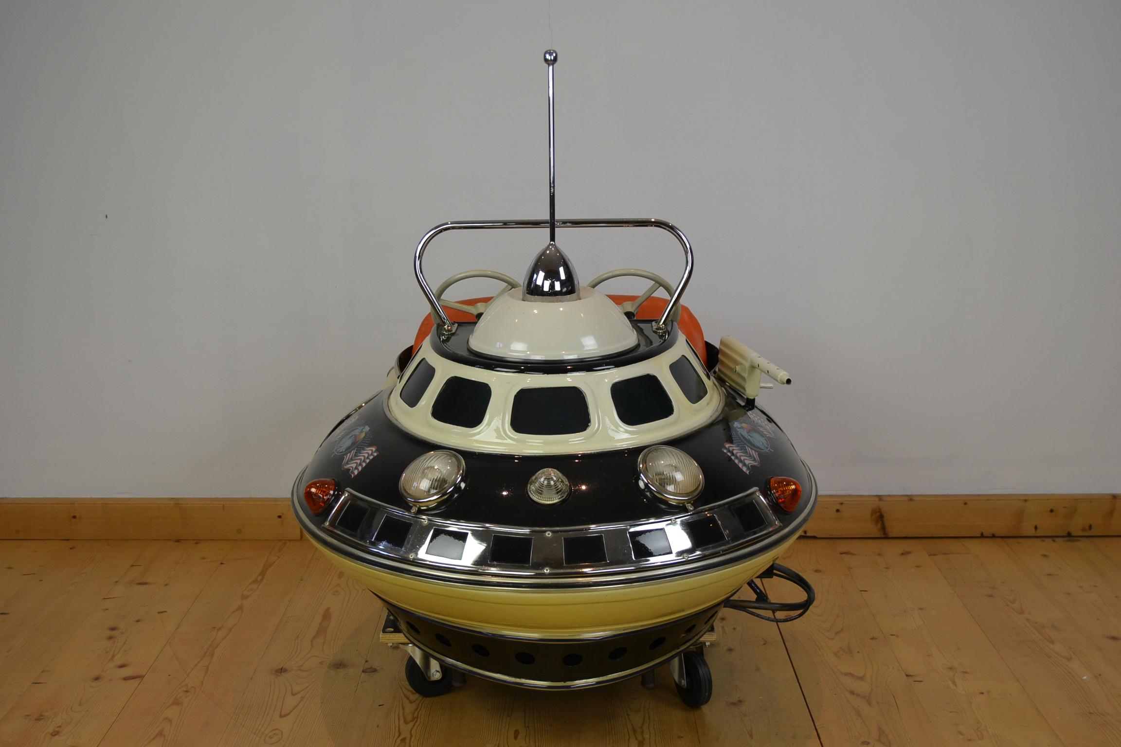 Space Age carnival ride seat in the shape of an UFO, made by L' Autopede Belgium.
This handmade metal 2-seat carousel ride object is in science fiction style and an awesome piece of carnival art. An astronautics shuttle for 2 children, still