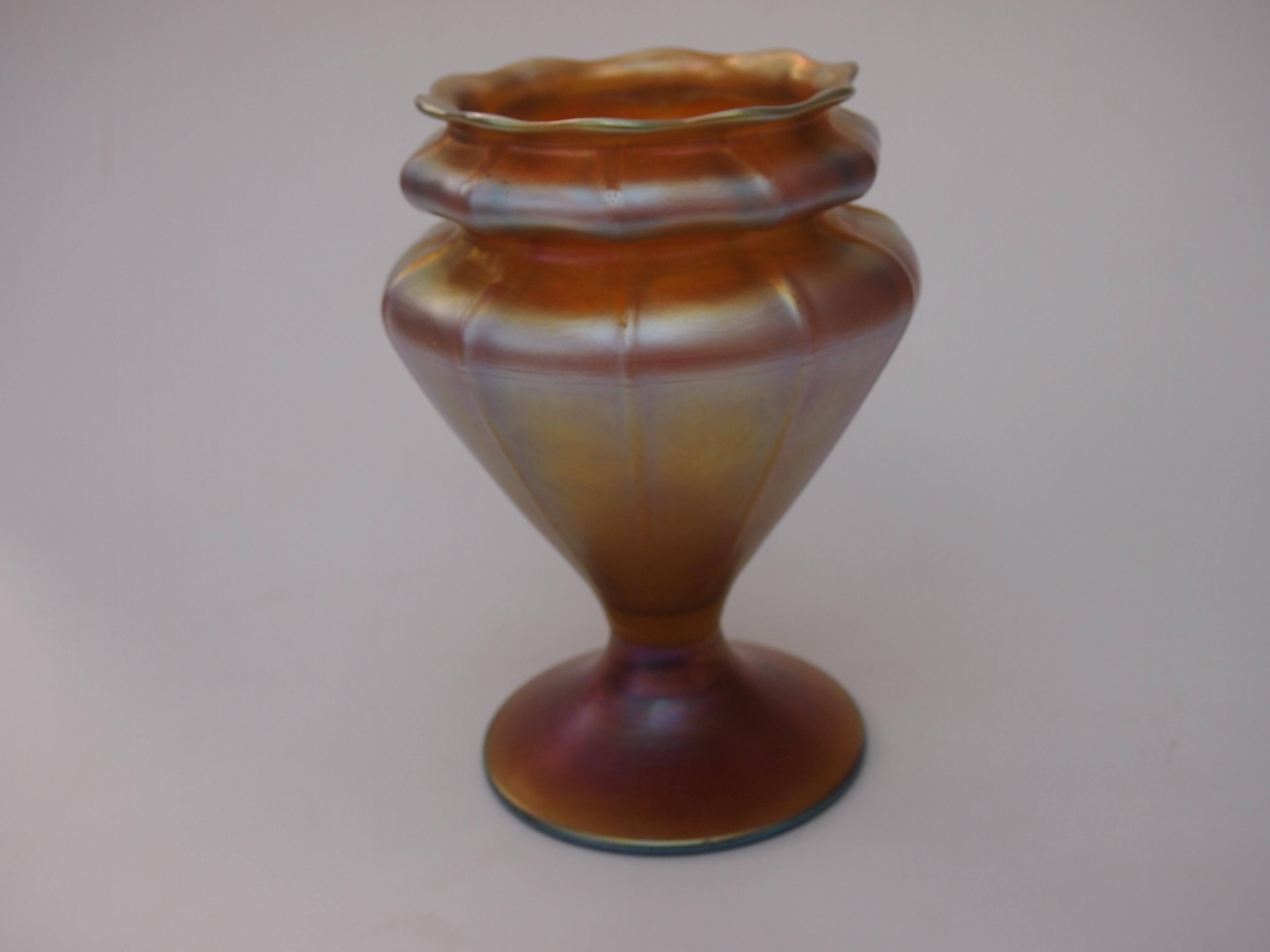 Fabulous footed L C Tiffany Favrile vase in iridised gold, ribbed, double waisted and with wavy top -in a good size-7 inches tall. Fully signed with shape code and production number.

Louis Comfort Tiffany was the son of the founder of the famed