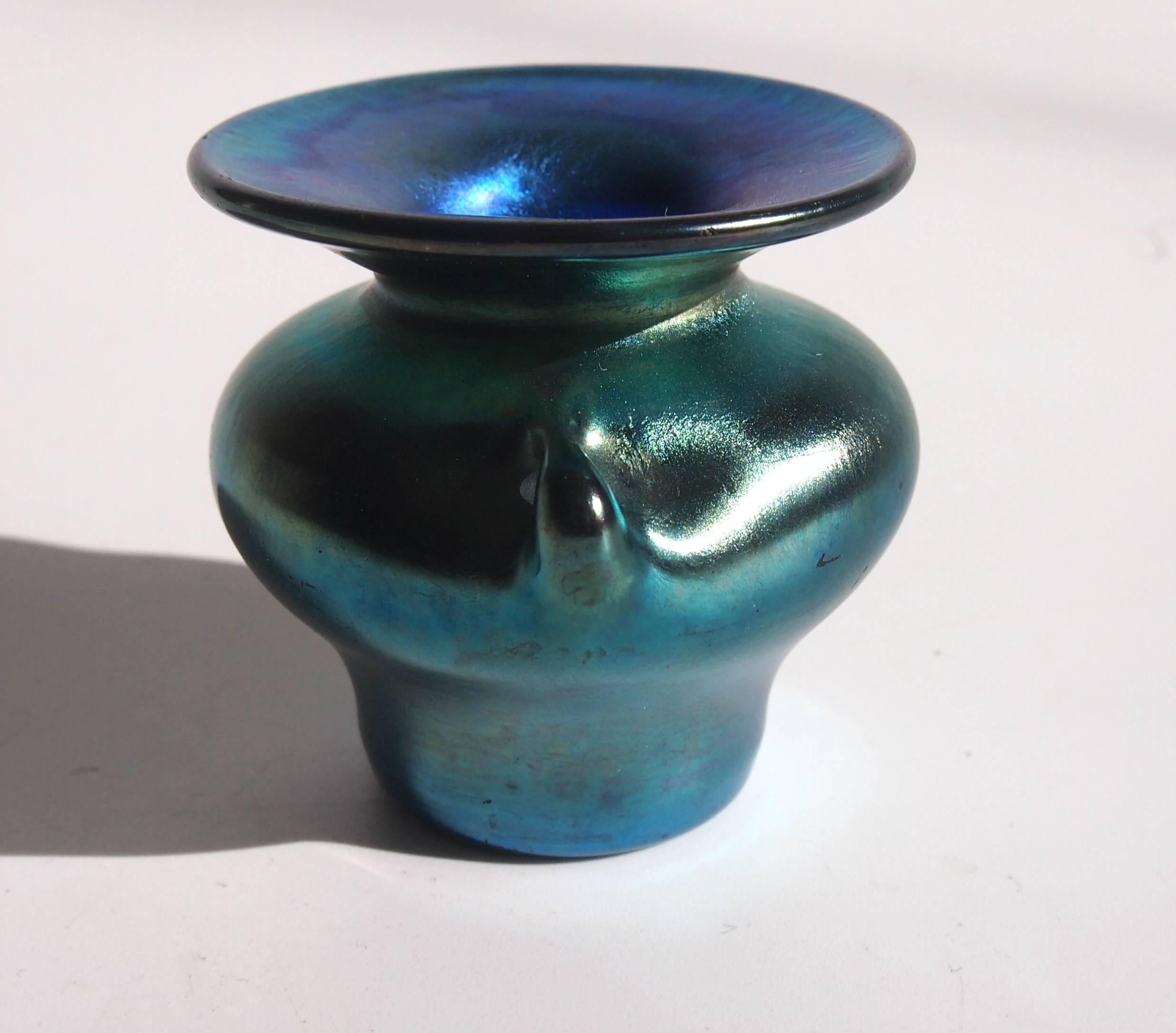 A very rare Louis Comfort Tiffany Art Nouveau blue Favrile miniature vase in the Art Nouveau style and shaped like a tiny Greek urn with two cute handles and flared opening top. The main body is a slightly greeny/gold blue and the flared opening is