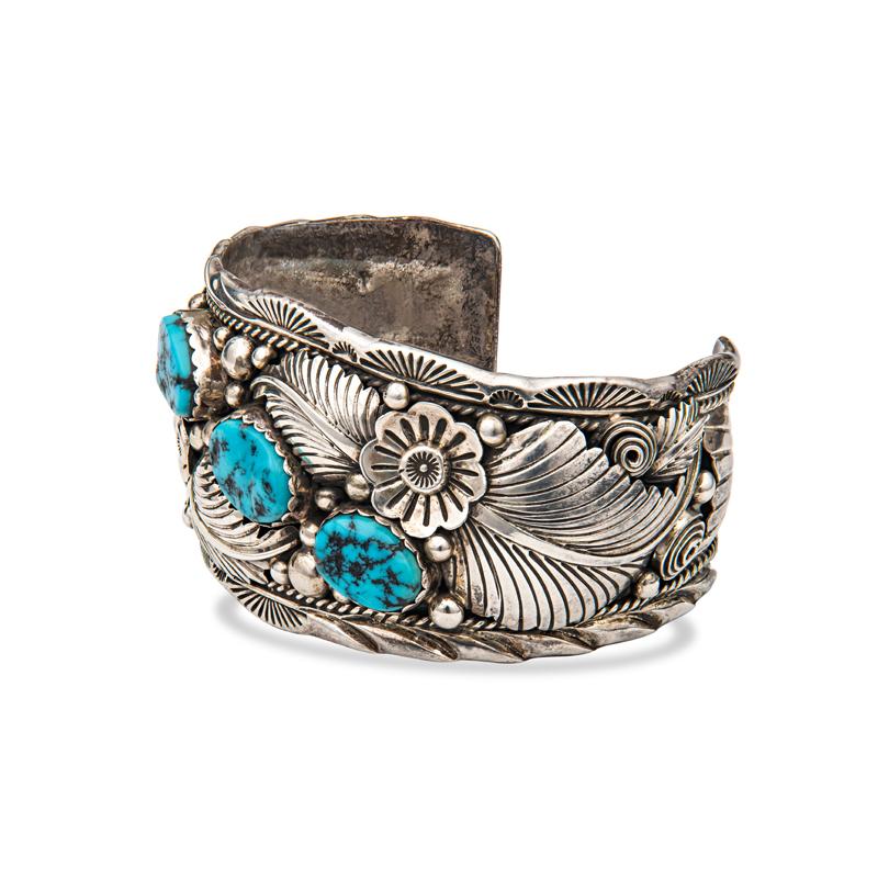 This antique sterling silver cuff features three large turquoise surrounded by intricate floral details that show off the turquoise stones. It measures approximately 1 5/8