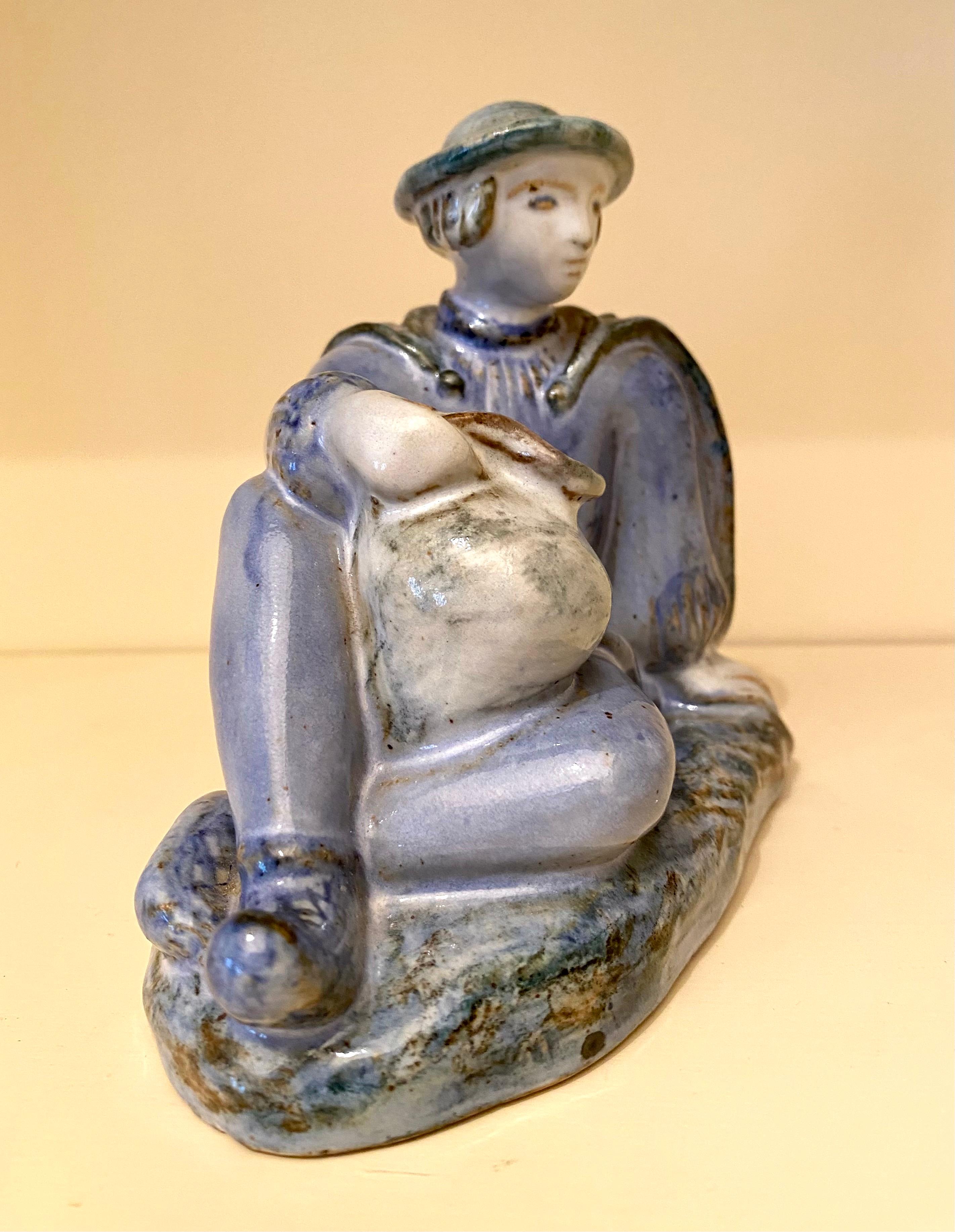 Estupenda cerámica danesa vintage de gres de L. Hjorth de un niño con una jarra en reposo. Su suave paladar azul y su arte hacen de ella una escultura única del siglo XX. Una gran pieza para cualquier colección de cerámica con mucha presencia para