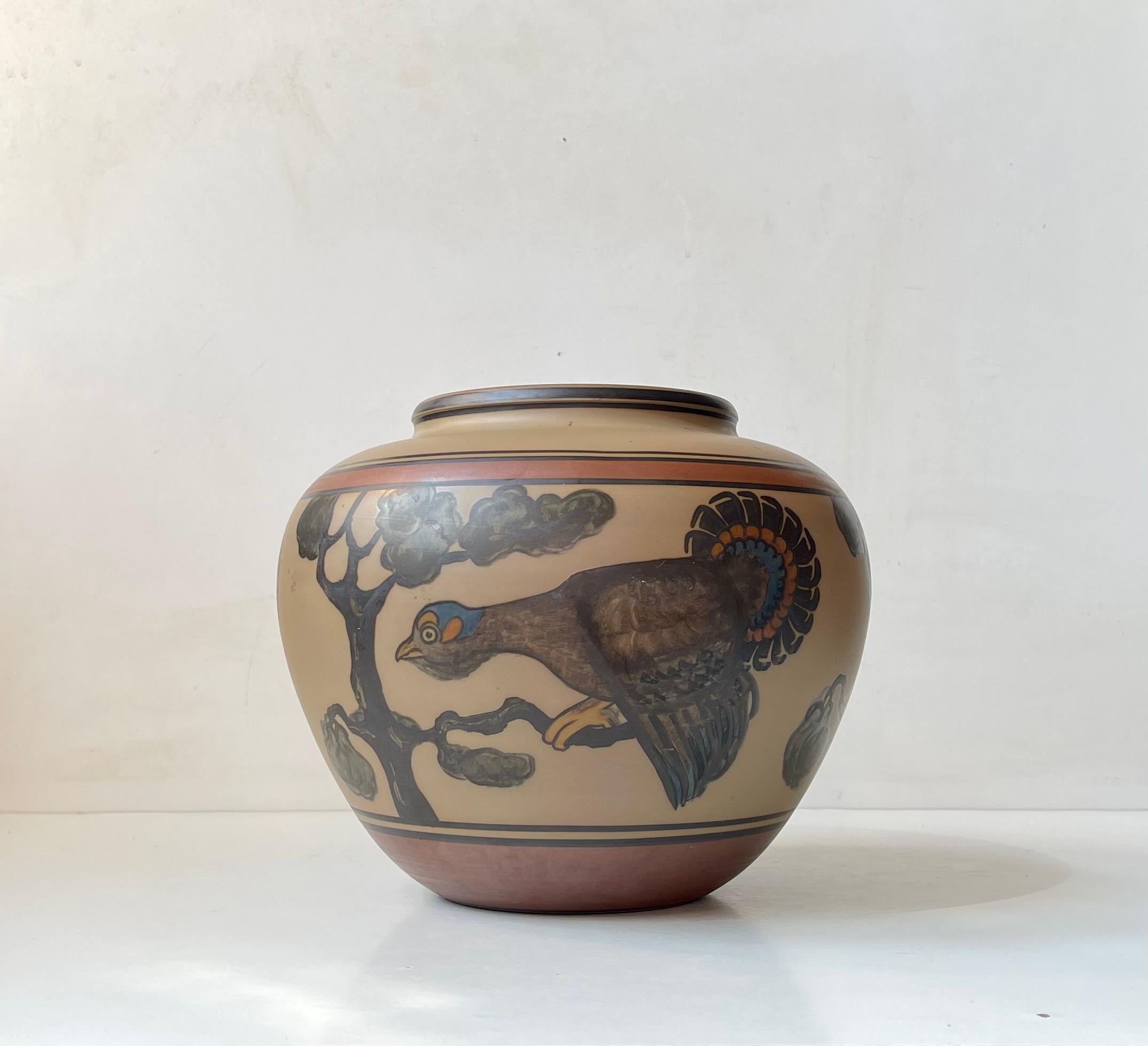 Große, seltene Vase aus handbemalter Terrakotta. Dekoriert in erdigen Glasuren mit floralen Impressionen und einem großen Pfau. Er misst 20 cm und hat einen Durchmesser von 23 cm. Unterzeichnet von L. Hjorth an der Basis. Es wurde in den 1940er