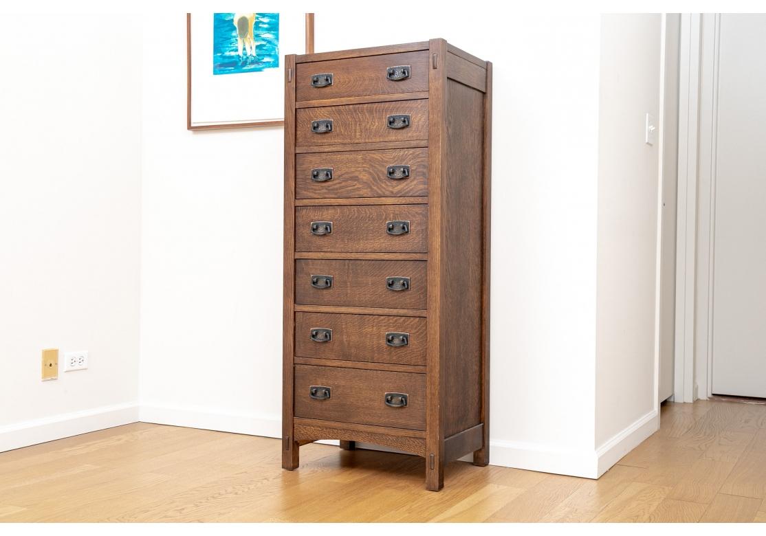 Stickley mission oak lingerie chest with 7 graduated drawers sporting hammered dark copper hardware and the top drawer with a green velvet sliding tray and the whole resting on straight legs. The top drawer flanked by exposed mortise & tenon