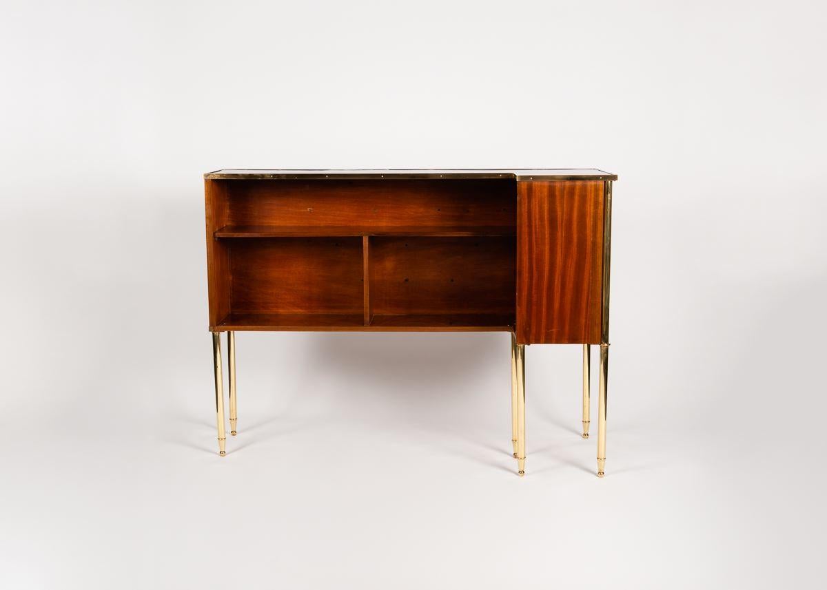This L-shaped, mid-century bar stands on slender gold-finish legs. Shelves line the interior for storage.
