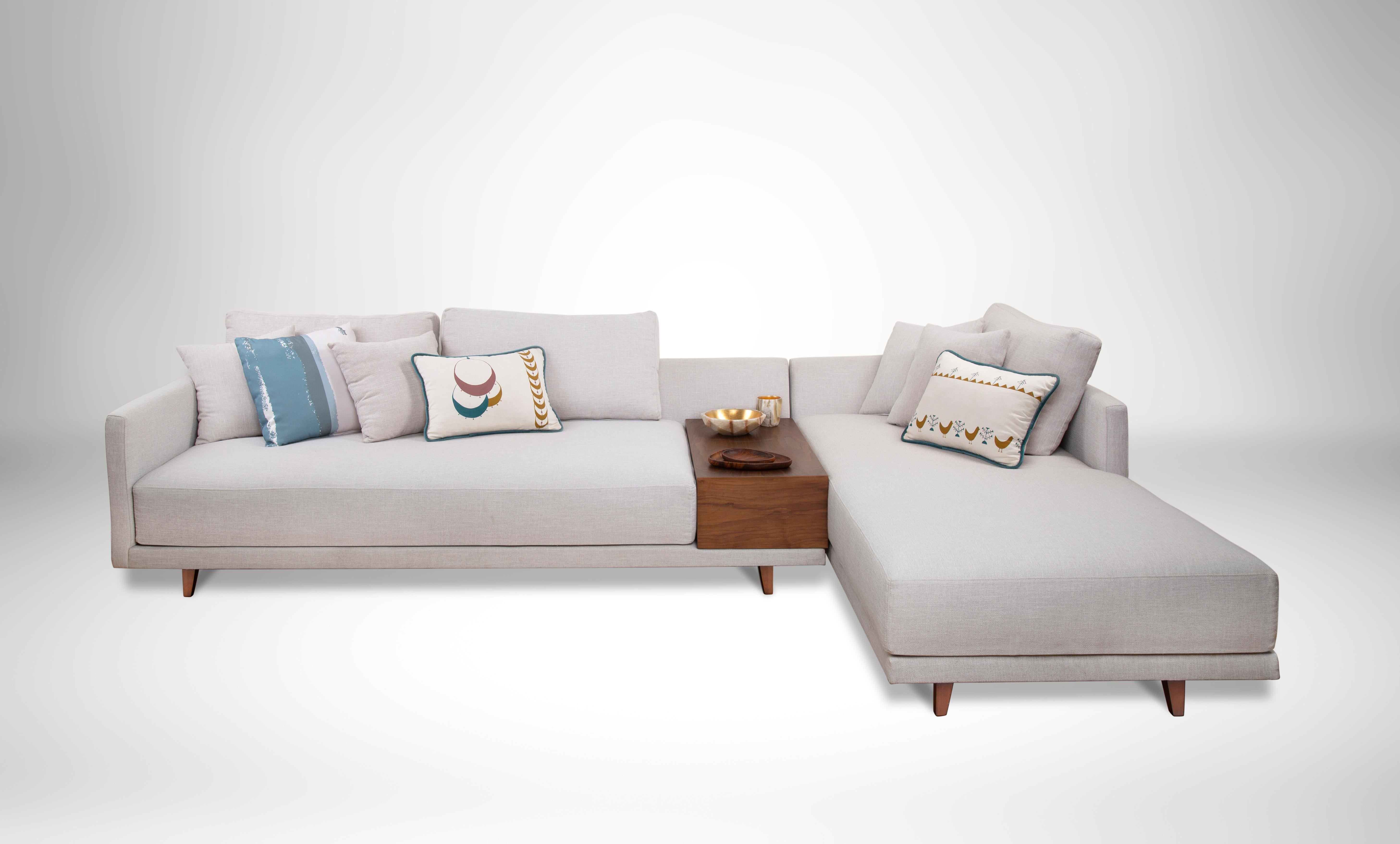 L-förmiges Sofa mit integriertem Beistelltisch aus Nussbaumholz mit Schaumstoff- und Faserfüllung.
Klare Linien und ein eingelassenes Tablett aus Walnussholz lassen dieses L-förmige Sofa wie eine schwebende Insel wirken. Das Gestell unseres