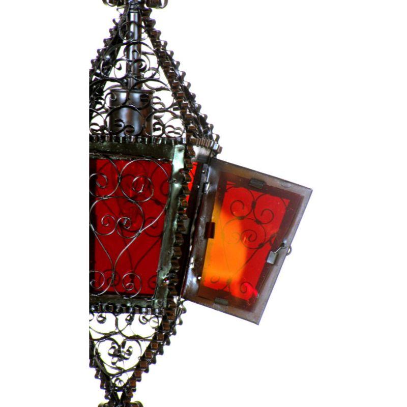 Handmade wrought iron lantern with a single light. wrought Iron has been hammered into ribbons and curled to make the shell of the lantern. Red glass panels. Slight irregularity of shape shows the handmade nature of the piece. 

Dimensions: