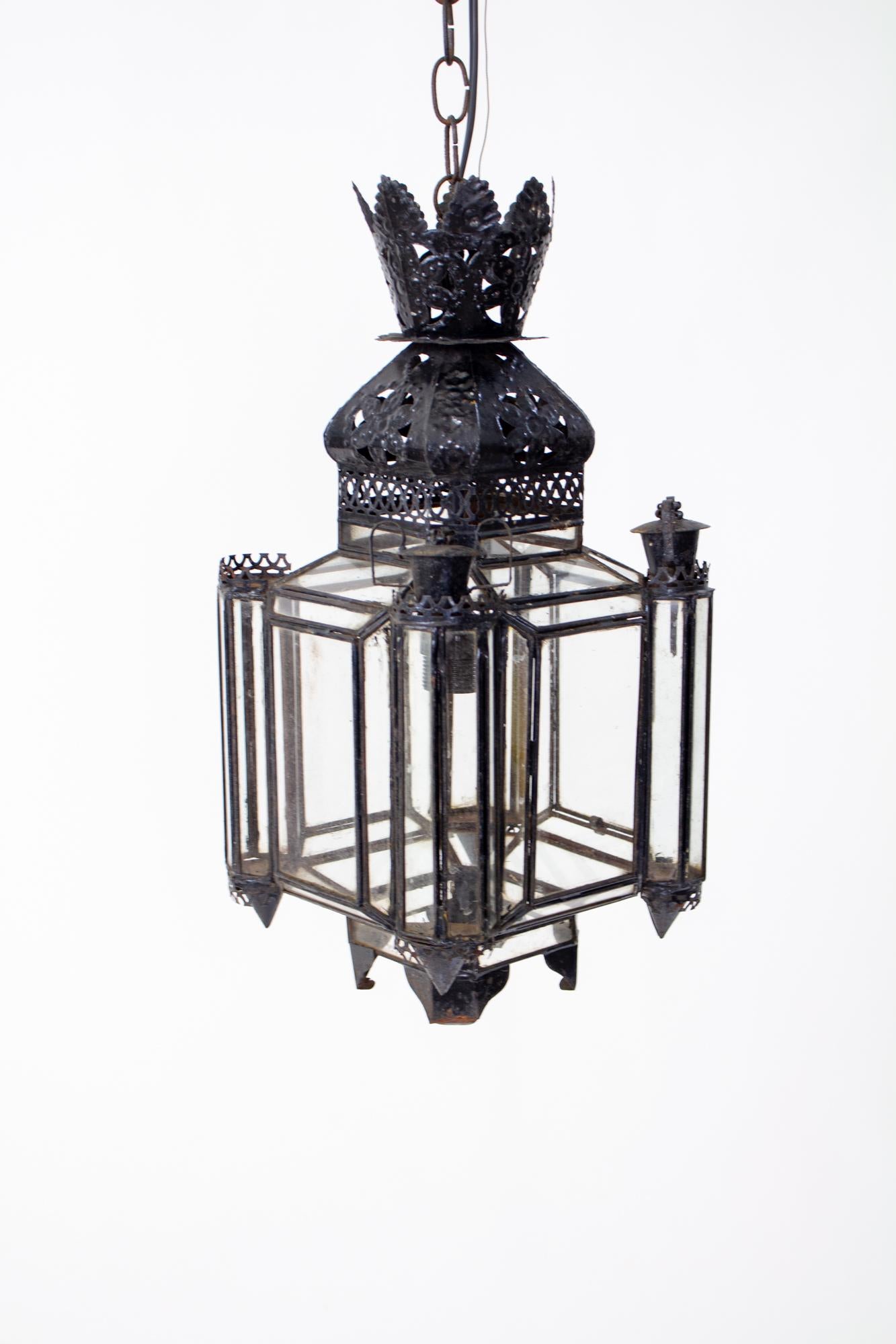 Mid 20th Century Moroccan tin lantern. Four sided with many glass panels. Lantern has been painted black and is aged with some rust. It is in shabby chic condition, rewired with a single bulb. 

Dimensions: 

Width: 9”
Depth:9”
Height: 24” overall,