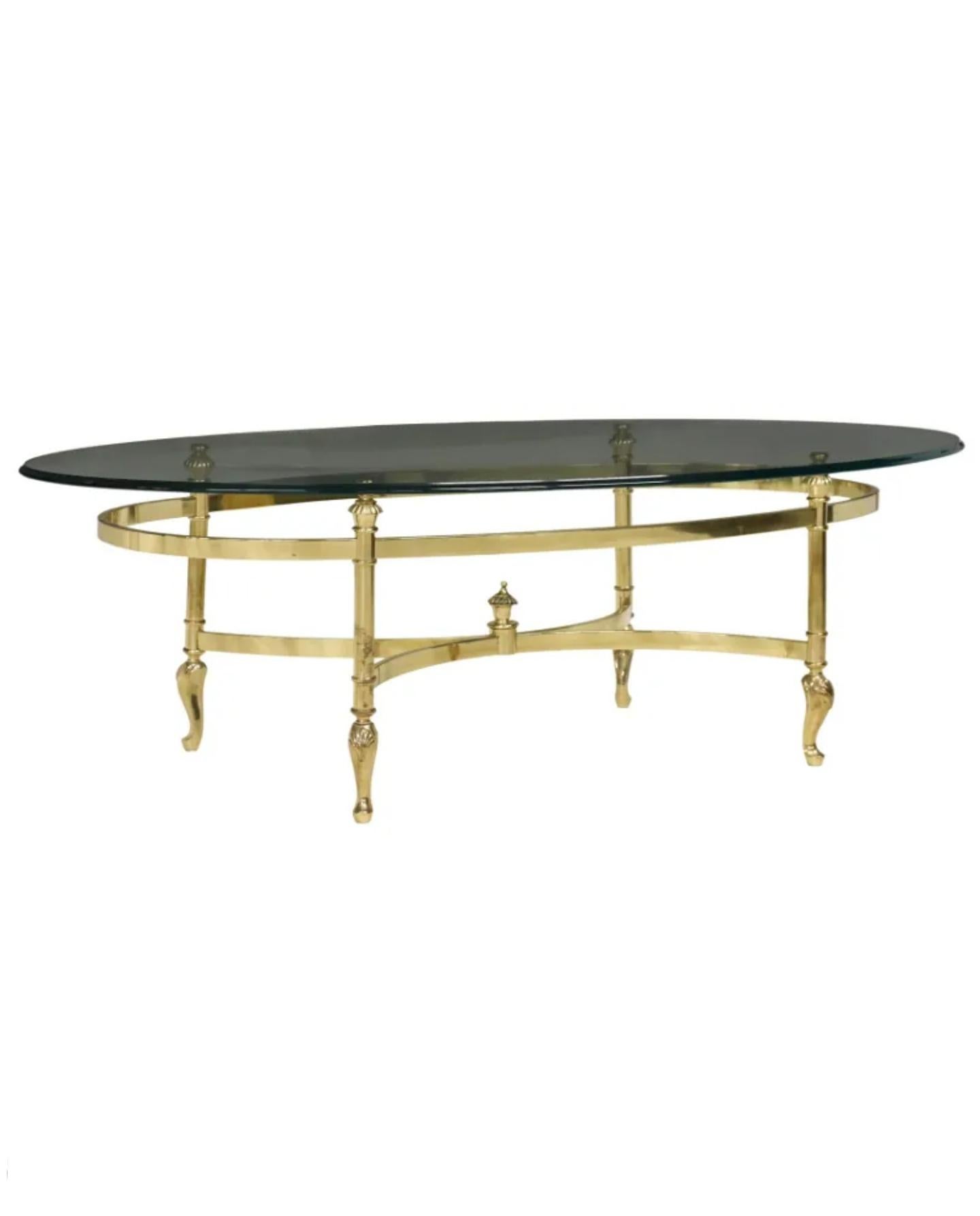 A fine quality Hollywood Regency style brass and glass oval coffee table, attributed to La Barge, second half of the 20th century, having beveled glass top, rising on finial topped X-form cross-stretcher base, ending on shell accented cabriole legs.