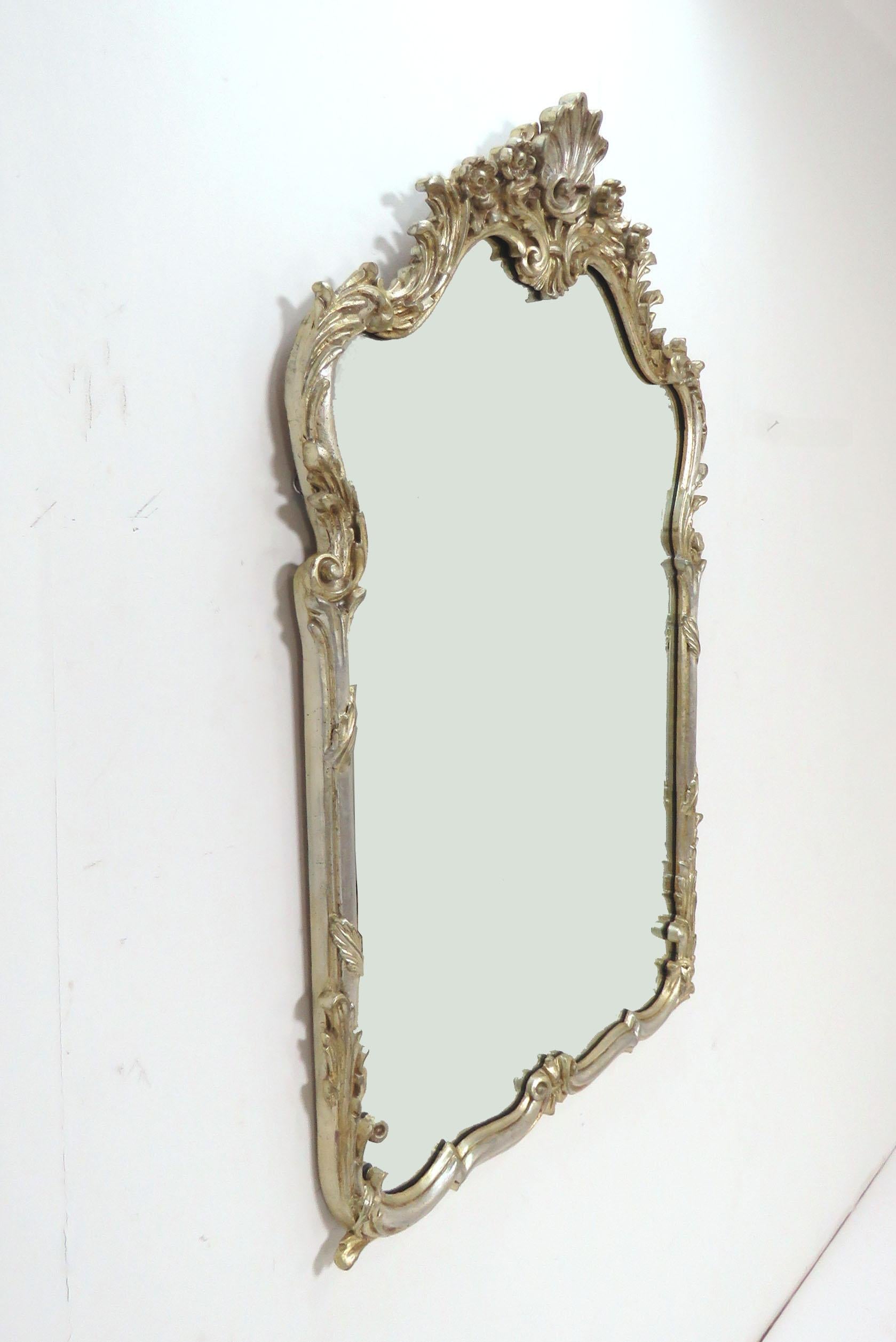 Wall mirror by La Barge in silver gilt with gold highlights, ornately carved. Made in Italy, circa 1960s.