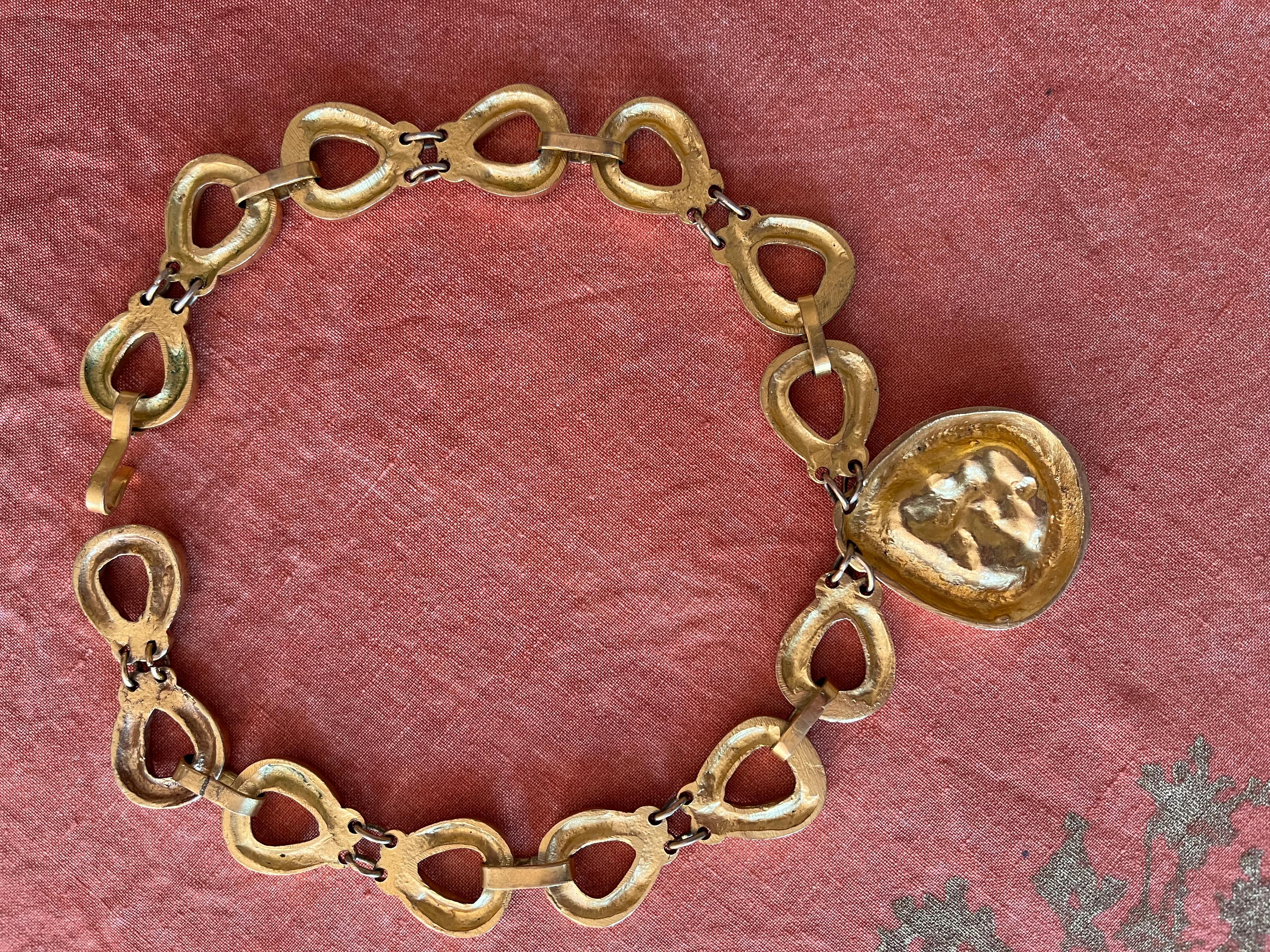 Collier articulé en bronze doré avec de larges maillons. Médaillon piriforme à décor en demi-relief figurant une colombe. Signé au dos du médaillon. H : 4,5 cm - 
 L : 26 cm 

La poésie, l'humour et l'inspiration de Line Vautrin (1913-1997) sont