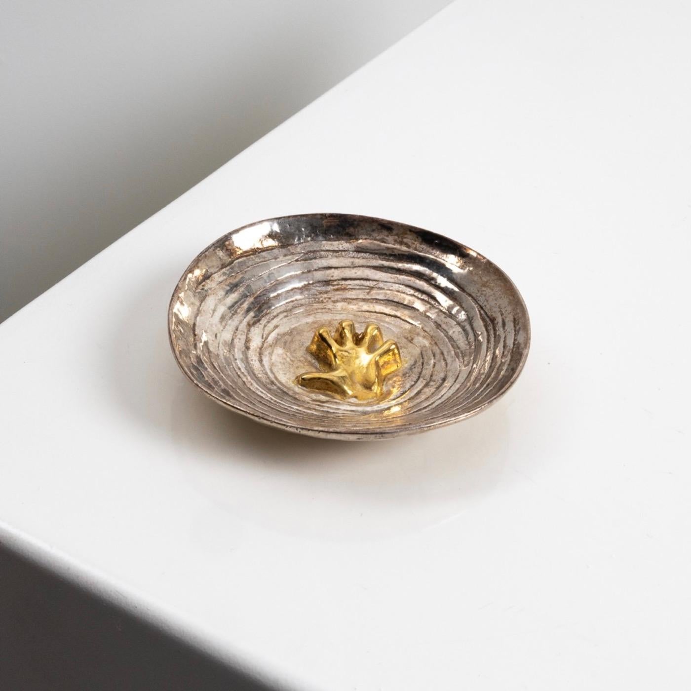 This pocket emptier reprensents a small hand in the sea waves.
The cup is made of silvered bronze while the hand is gilded.
The theme of the sea, recurrent in the work of Line Vautrin is used here for this poetic object of which we know several