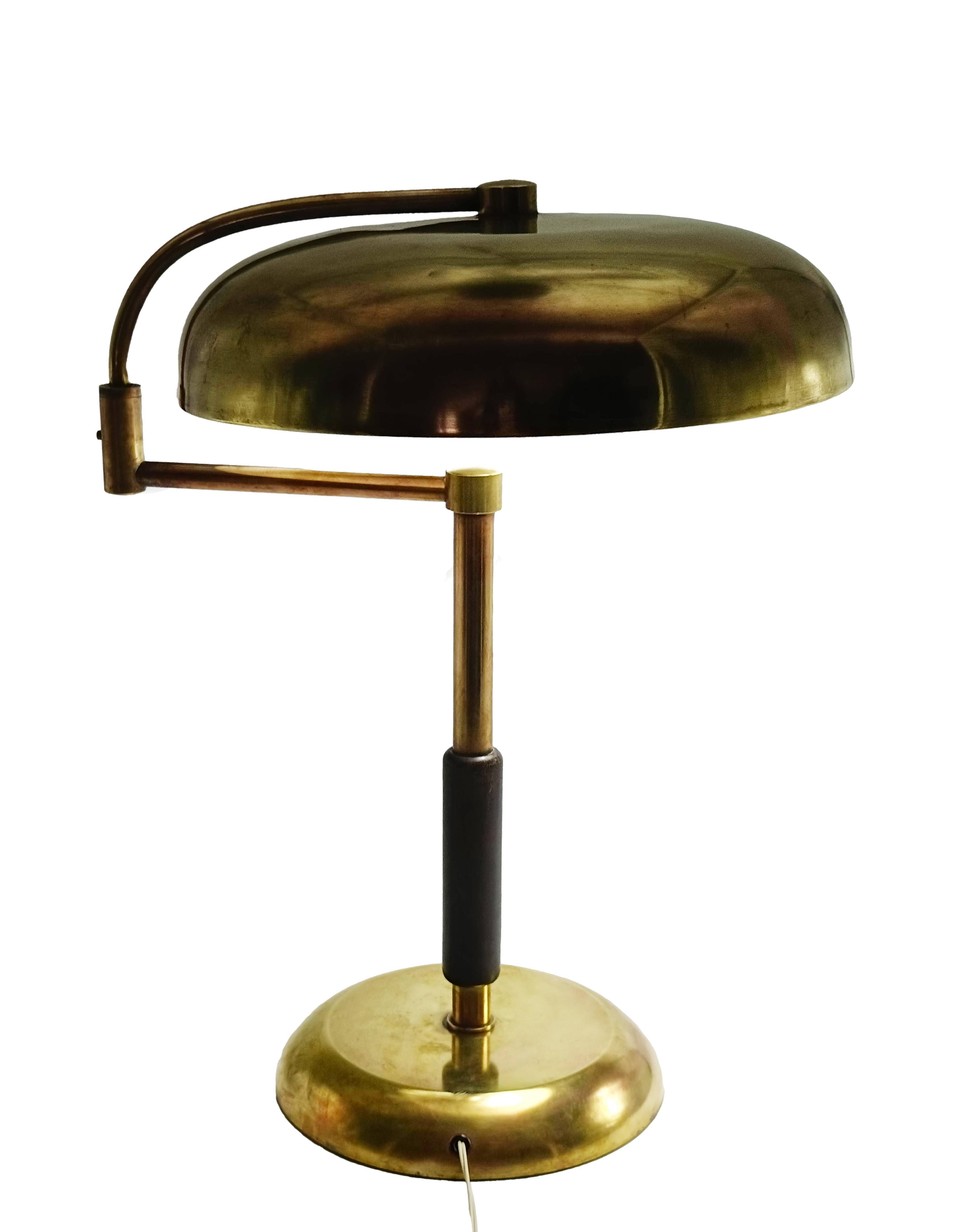 Brass desk lamp by Maison Desny characterized by elegant, geometric lines and a minimalist design. It features a brass base and stem with a wooden accent and an adjustable arm that allows the user to direct the light where needed. 
Today, the Maison