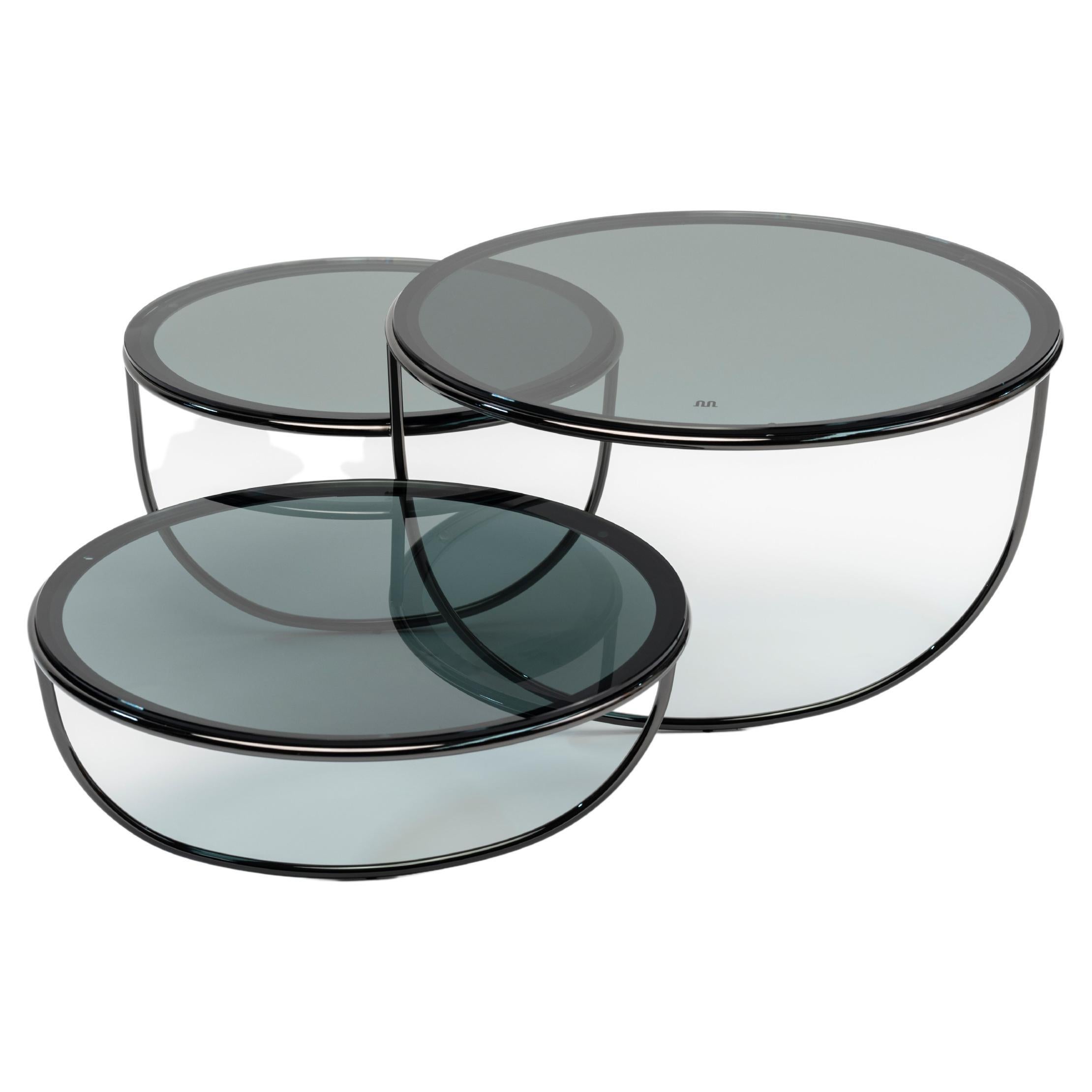 À première vue, Trio est une table d'appoint composée de trois bols transparents qui se chevauchent.
L'ouverture de chaque bol est recouverte d'un plateau en verre, en métal ou en bois. La forme du bol est suggérée par une seule ligne courbe - un