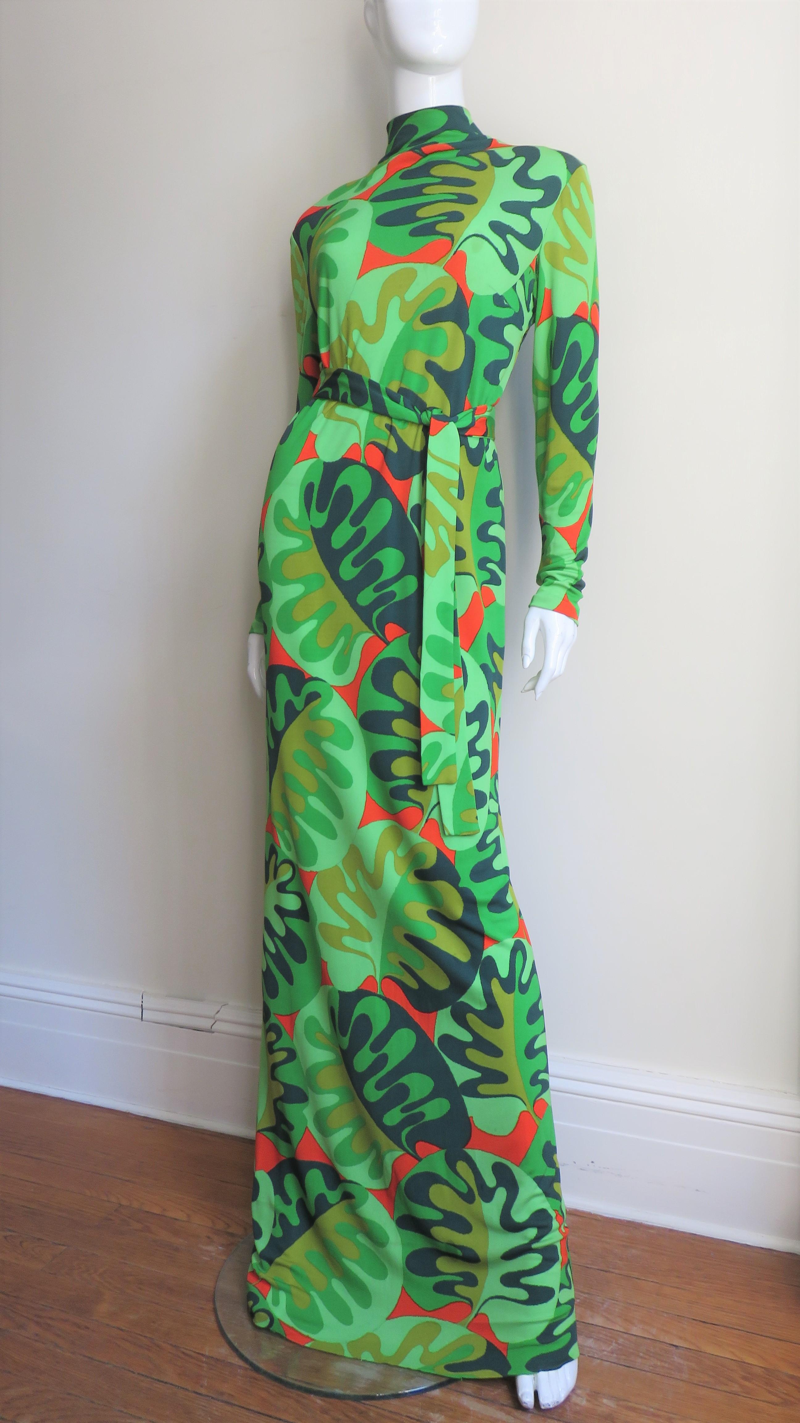 A gorgeous fine silk jersey maxi dress and matching sheer silk overskirt from La Mendola in an abstract greens and red pattern. The dress has long sleeves, a standup collar and a matching tie belt.  It comes with a matching semi sheer silk full