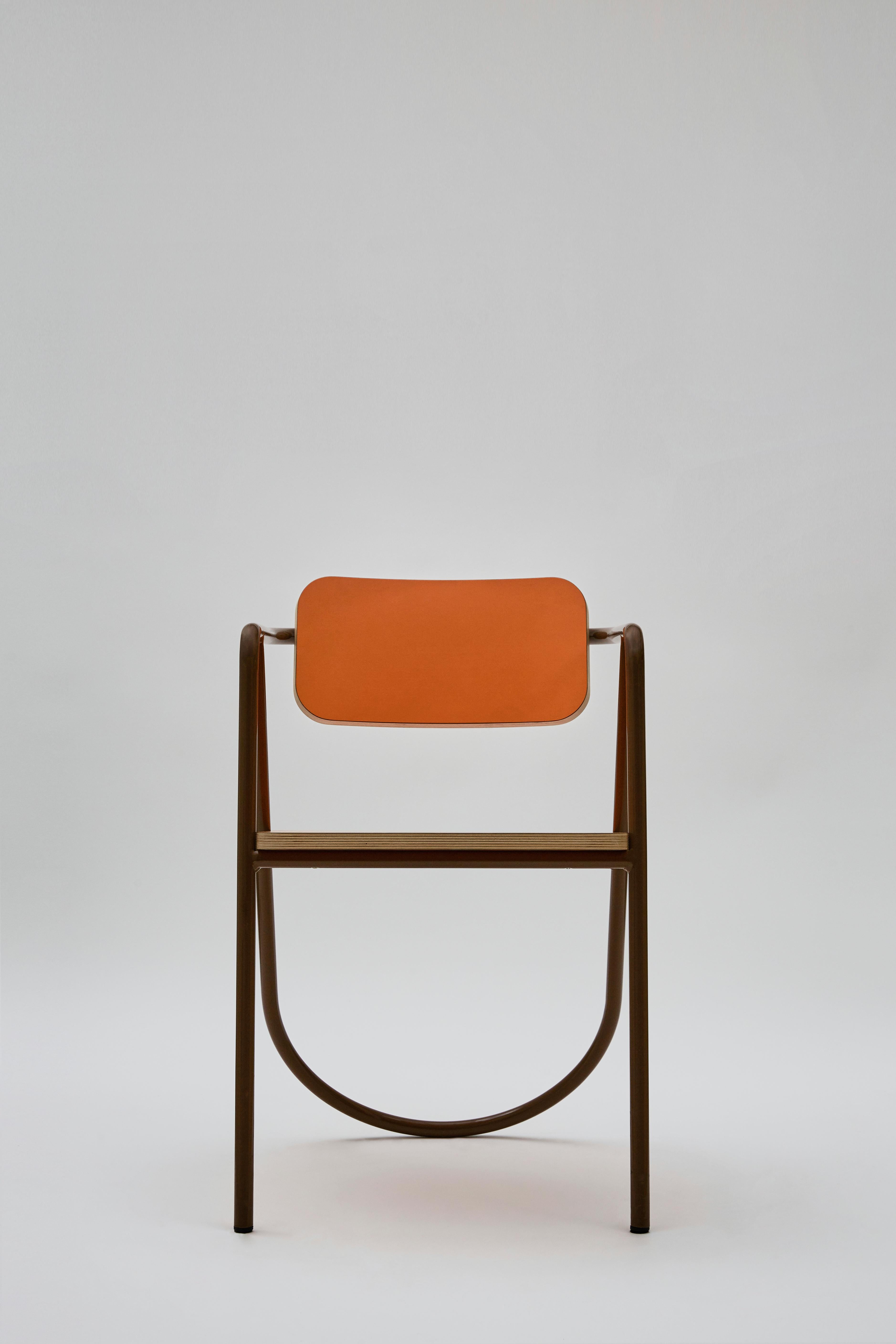 Vintage and contemporary references merge in this sculptural armchair from the La Misciù Collection. The wooden backrest and seat, softened by rounded corners and accented with a vivid orange shade, are fitted to a dramatic tubular steel frame