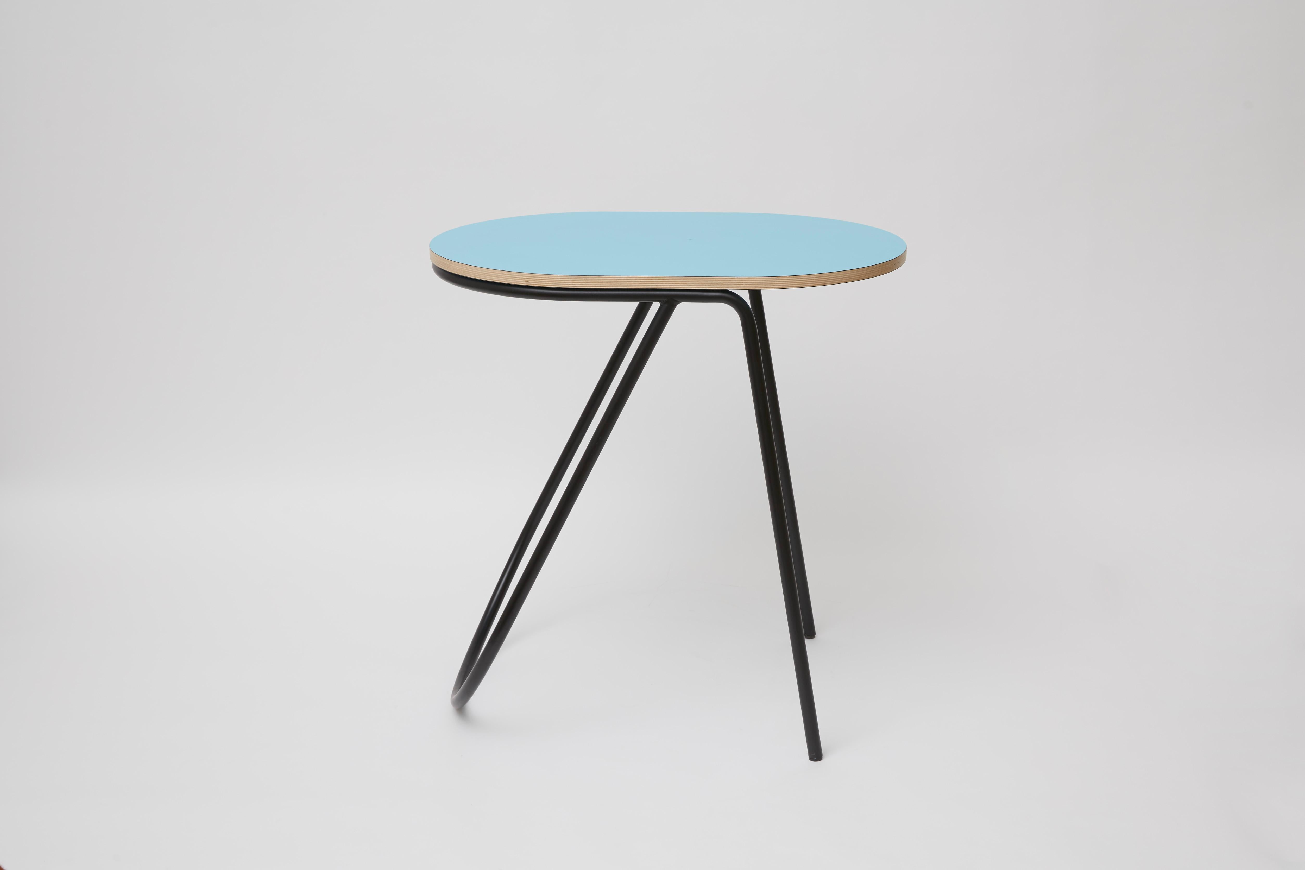 A quiet asymmetrical twist distinguishes this round side table from the La Misciù Collection. The wooden top finished in light-blue rests on an airy cylindrical steel base comprised of two front legs and of a U-shaped element offering efficient rear