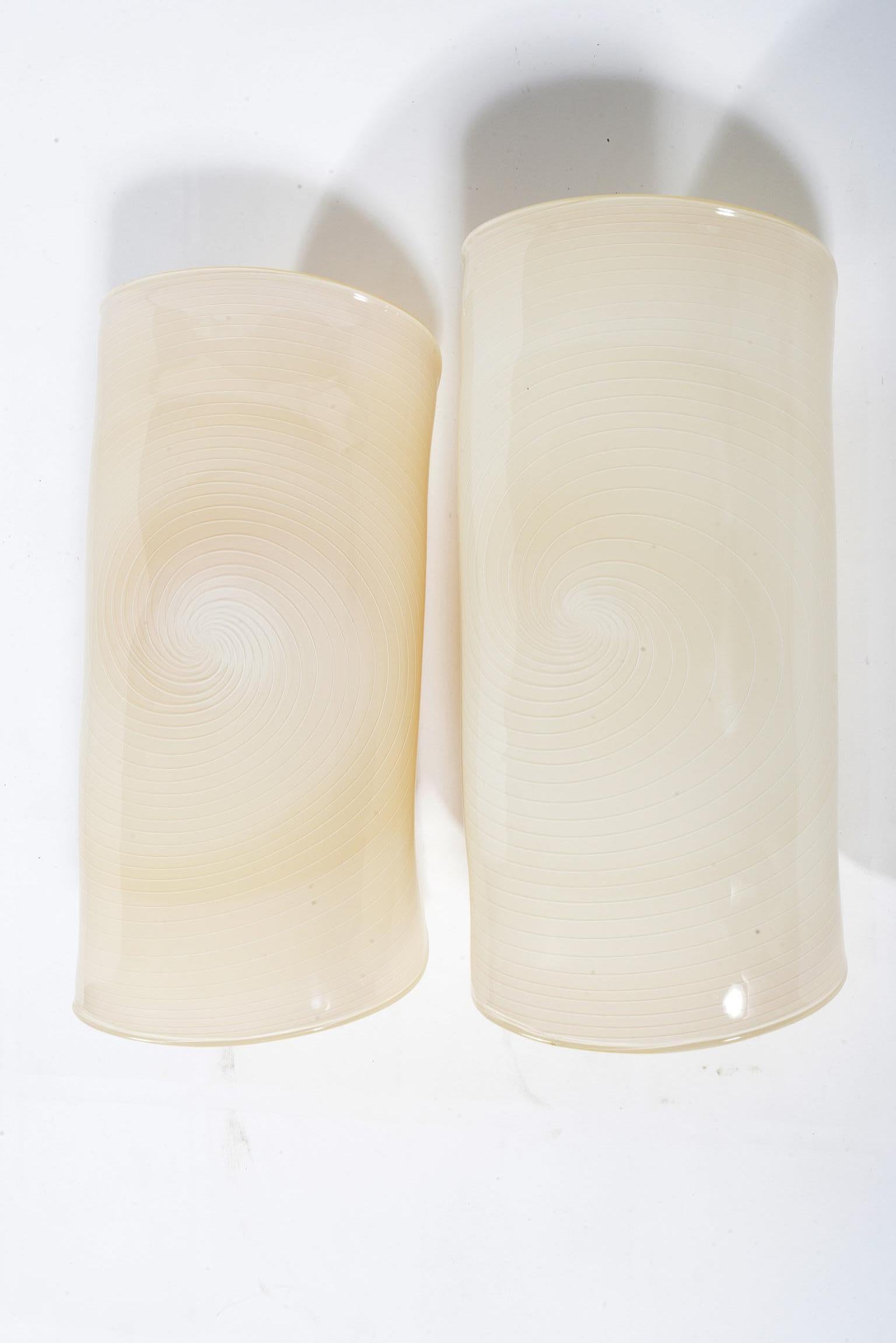 Pair of appliqués produced by La Murrina Murano Manufacture in the 1970s by blowing a disc in beige glass with a spiral of white glass, the disc was then folded when still hot to create the appliqué. The glass when it lights up reveals the light
