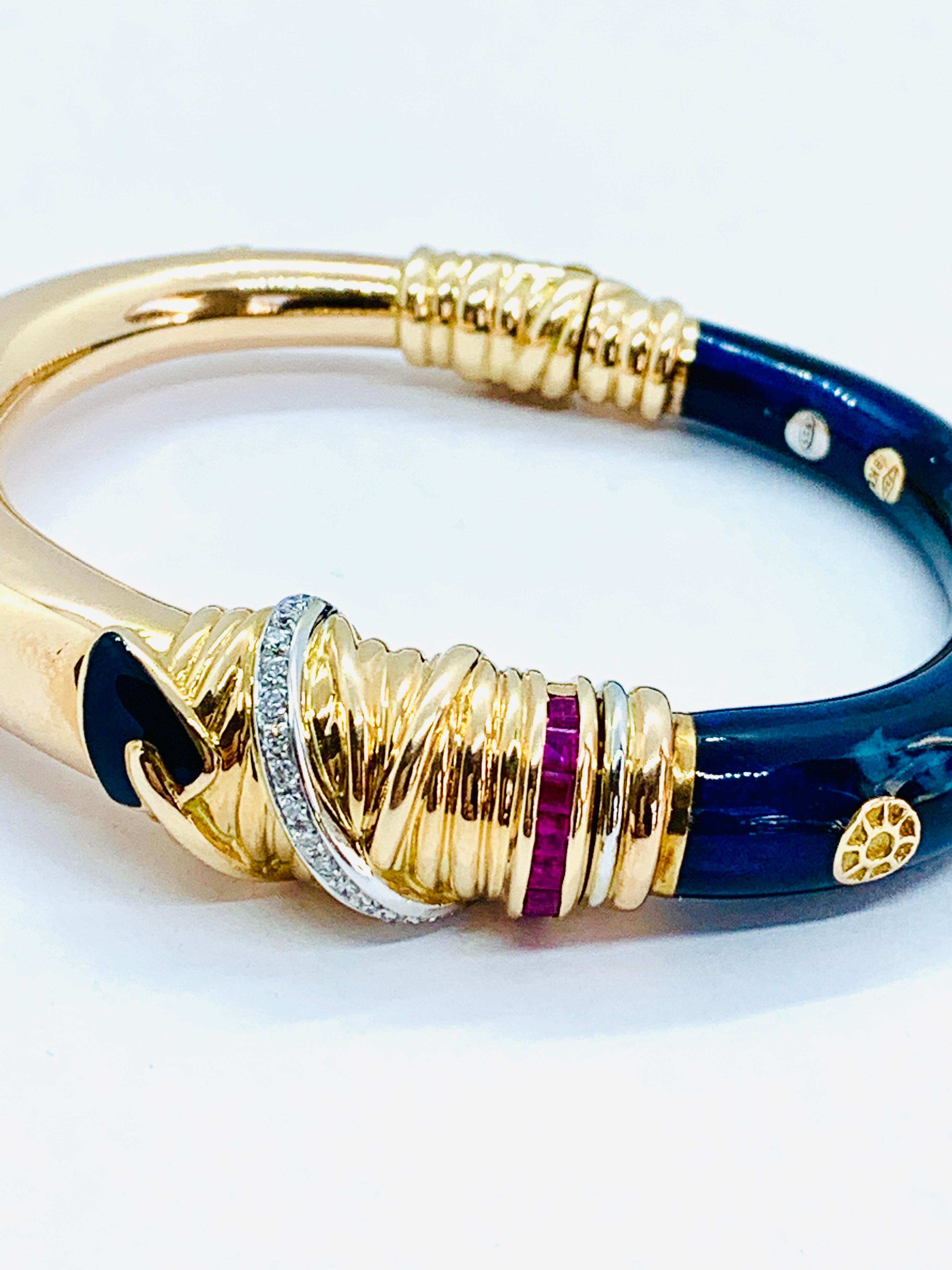Gorgeous La Nouvelle Bague Bangle Bracelet. Made in 18K Yellow Gold and sterling silver with a single brand of square baguette rubies as well as a band of 16 diamonds.. One side has gorgeous Blue enamel. Will fir up to a 6 inch wrist and weighs 49.6