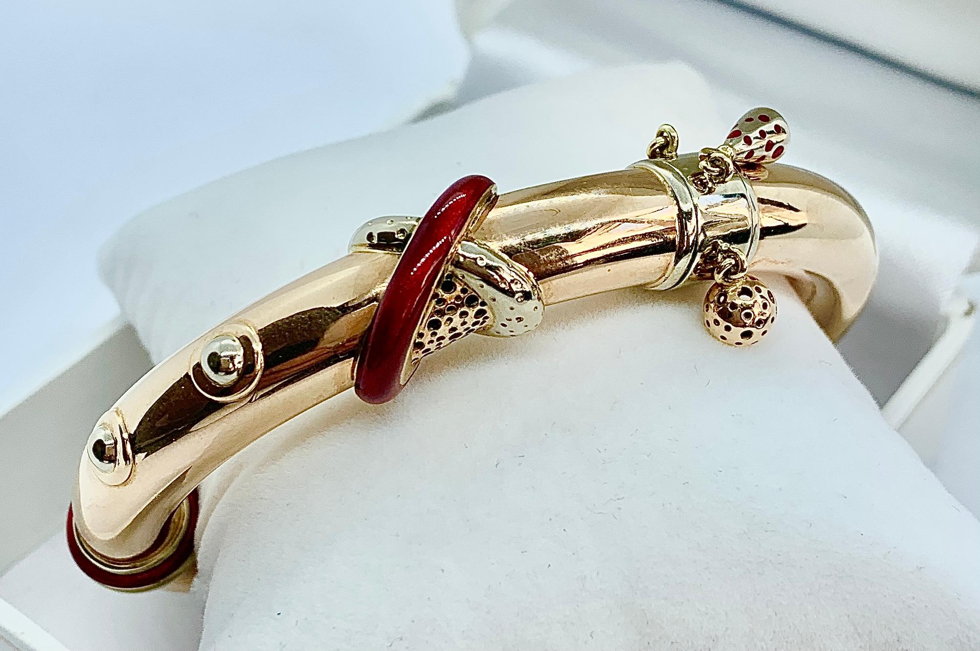 Gorgeous La Nouvelle Bague Bangle Bracelet. Made in 18K Yellow Gold with red enamel accents as well three charms. Please view the video in the listing to see the movement of the charms and how the bracelet opens and closes. Will fit up to a 6 inch