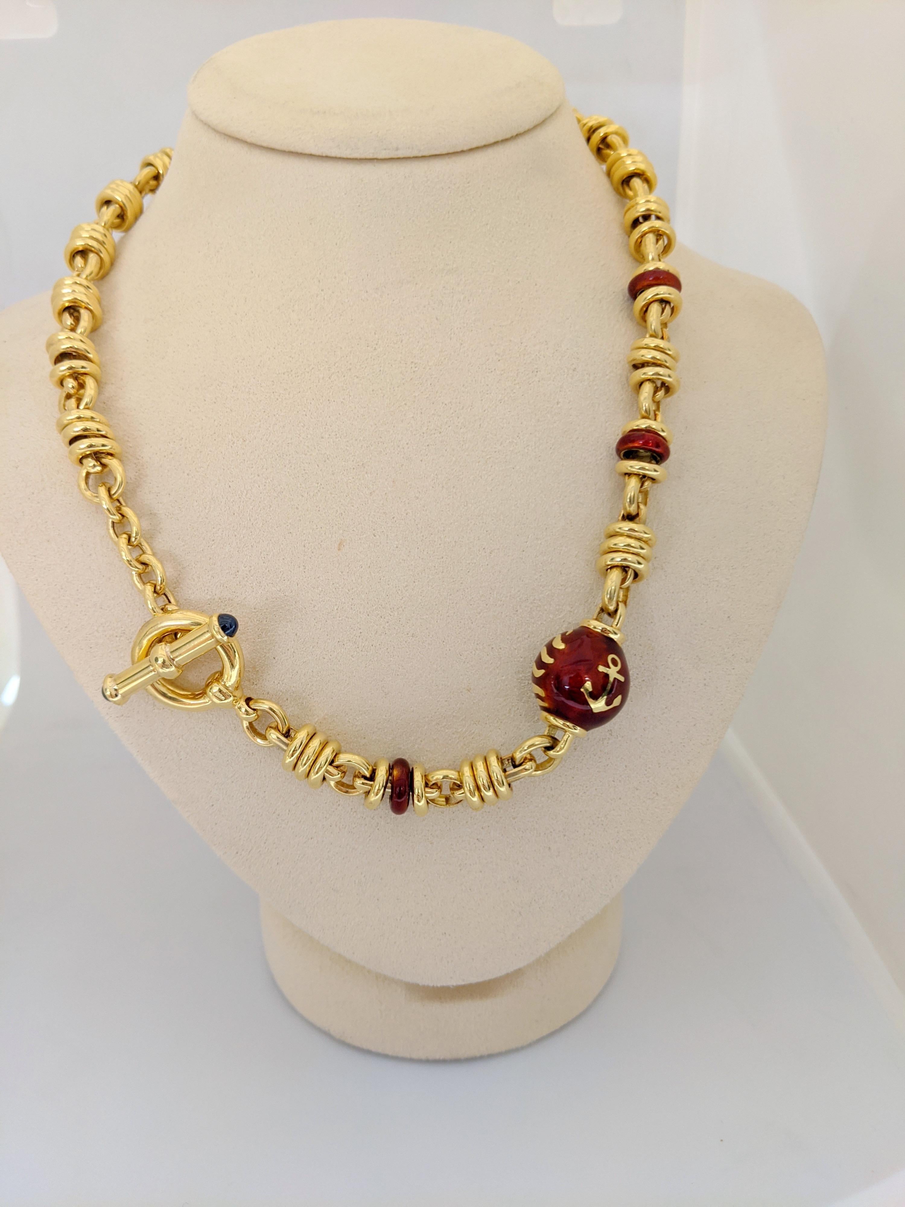 Designed by La Nouvelle Bague from Italy.  This 18 karat yellow gold link necklace features a burgundy enamel ball and a few enamel rondelles. The necklace has a toggle closure that is accented with Blue Sapphire cabachons. The necklace measures
