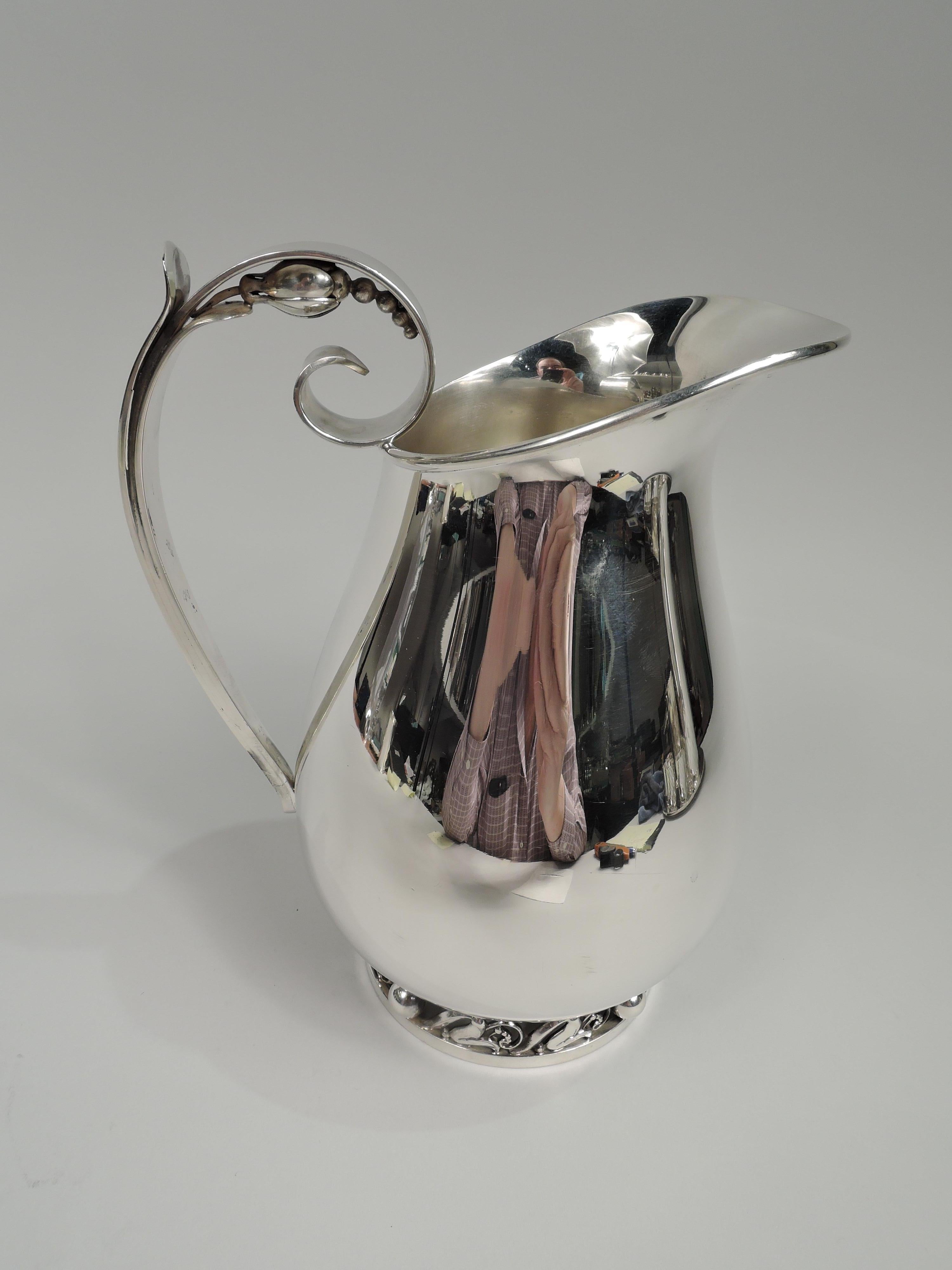 Mid-Century Modern sterling silver water pitcher. Designed by Alphonse La Paglia (d. 1953) for International Silver Co. in Meriden, Conn. Baluster with helmet mouth. Capped high-looping handle with volute-scroll terminal mounted with Blossom-style