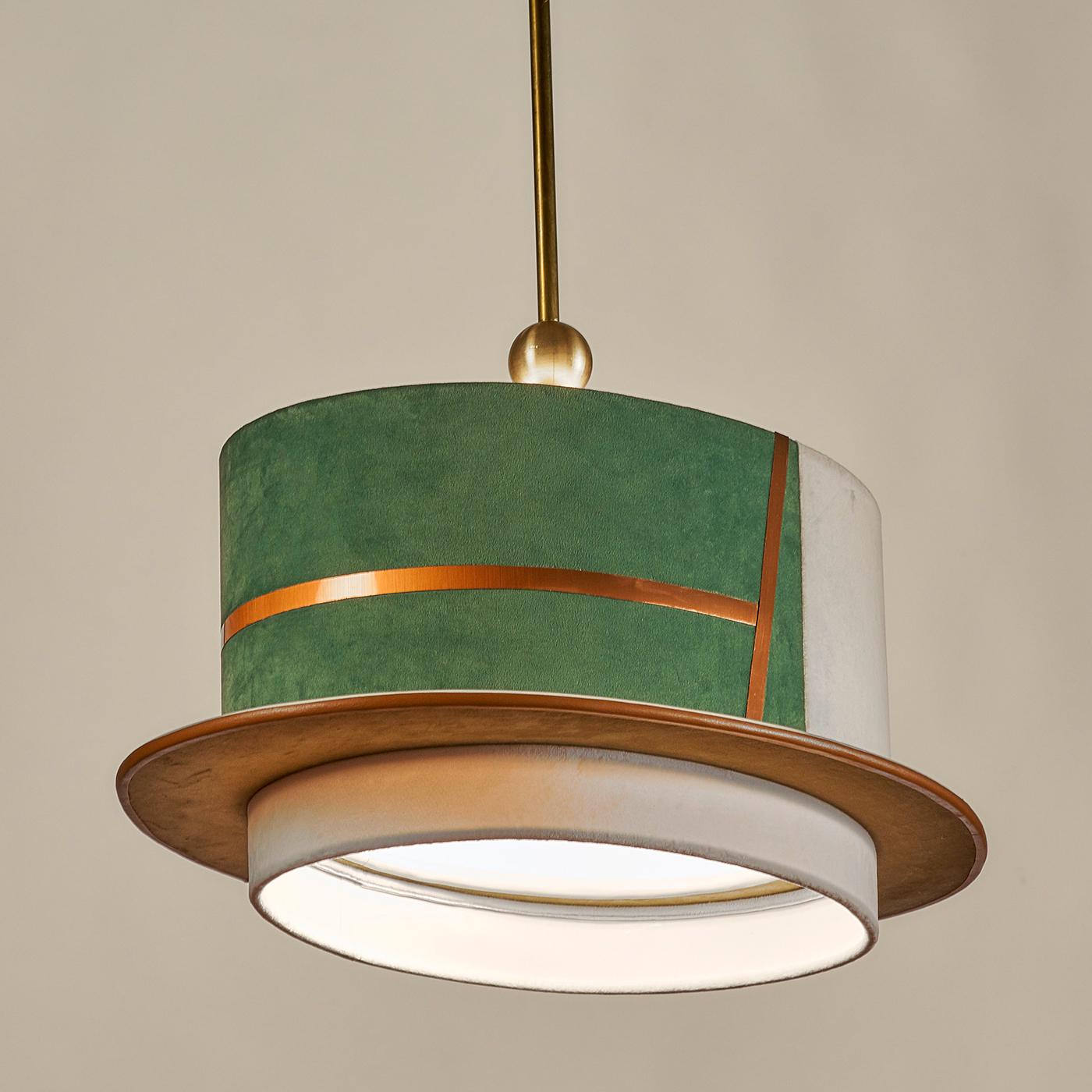 Part of the Capeau collection inspired by the world of hats, this pendant light evokes the shape of the hat worn by Venetian gondoliers. Entirely crafted of fine velvet with trims in ivory and copper leather, the oval lampshade showcases an elegant